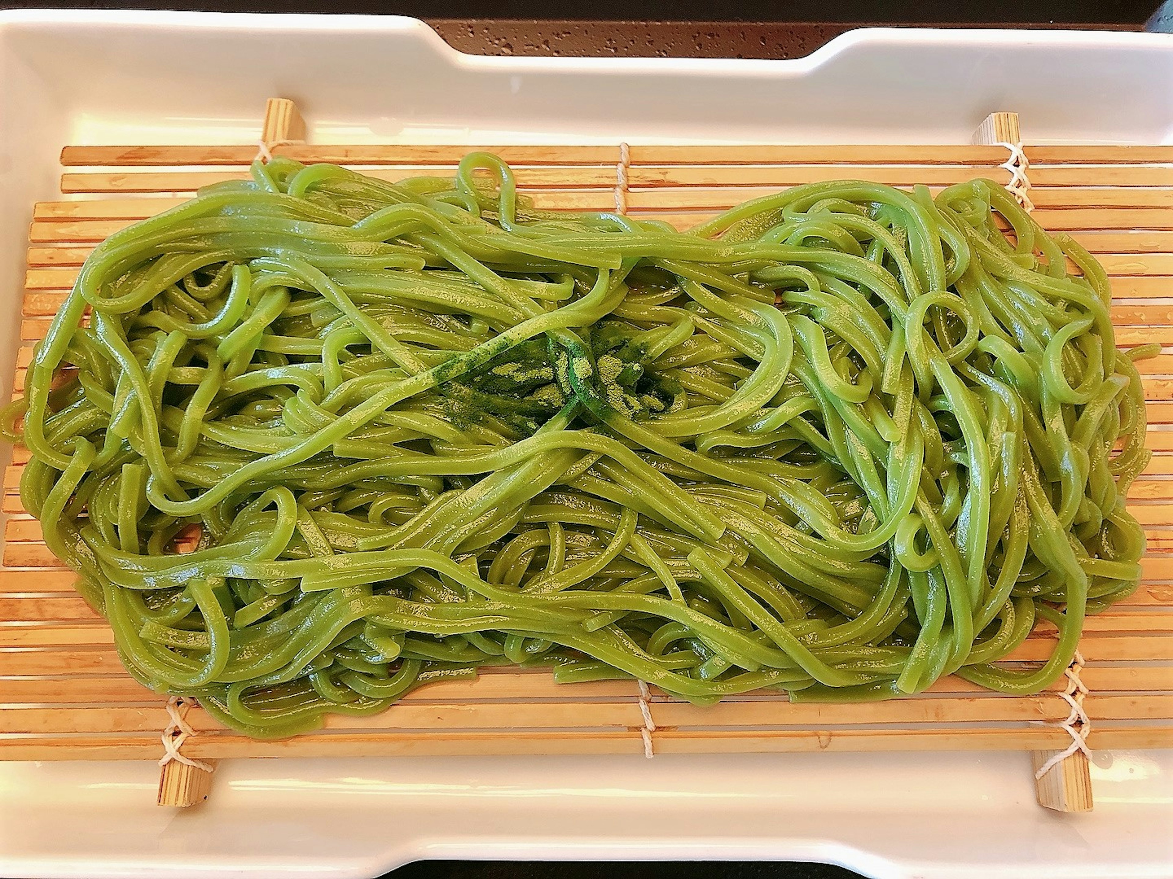 Green noodles arranged on a bamboo mat