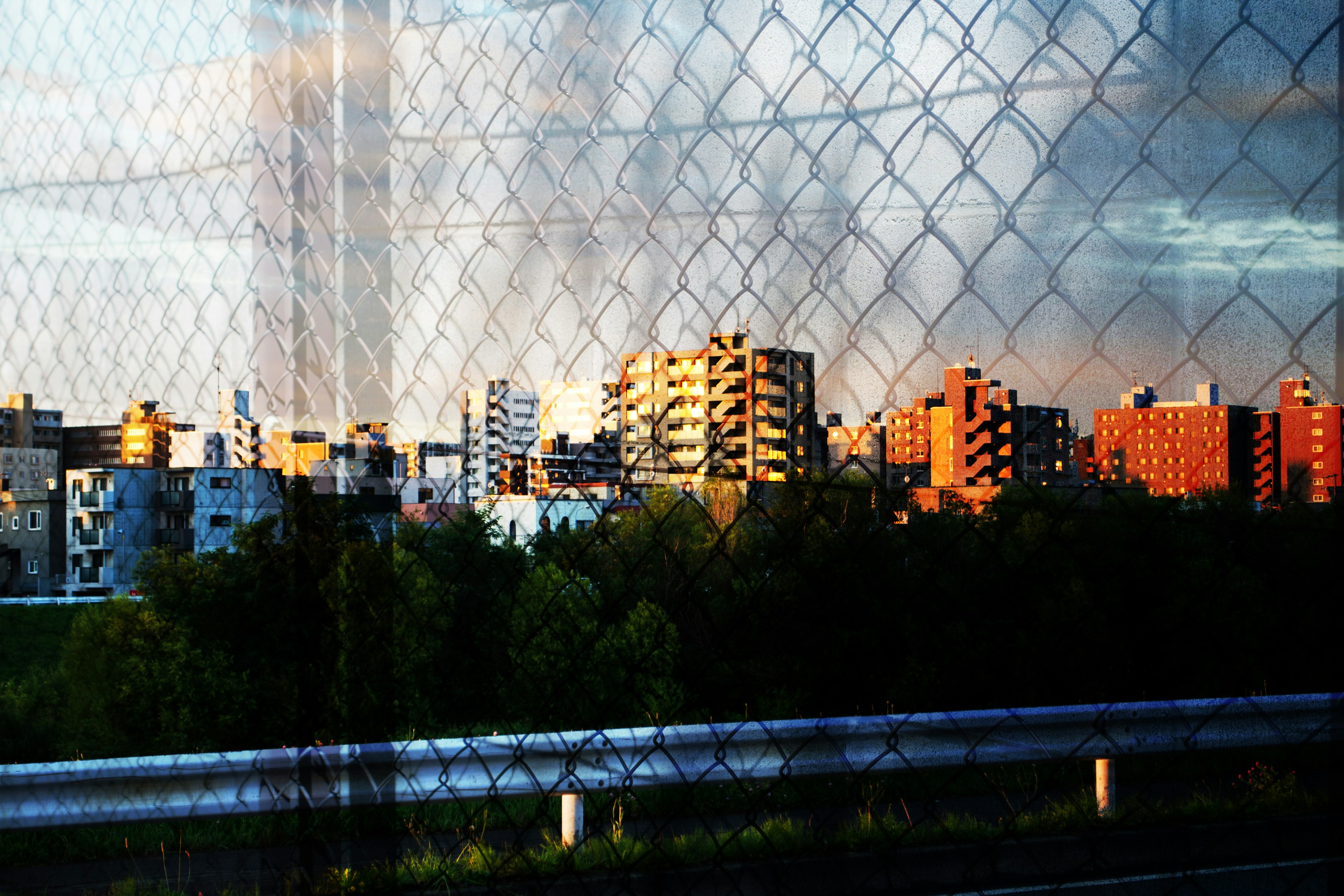 Cityscape viewed through a fence with sunset lighting