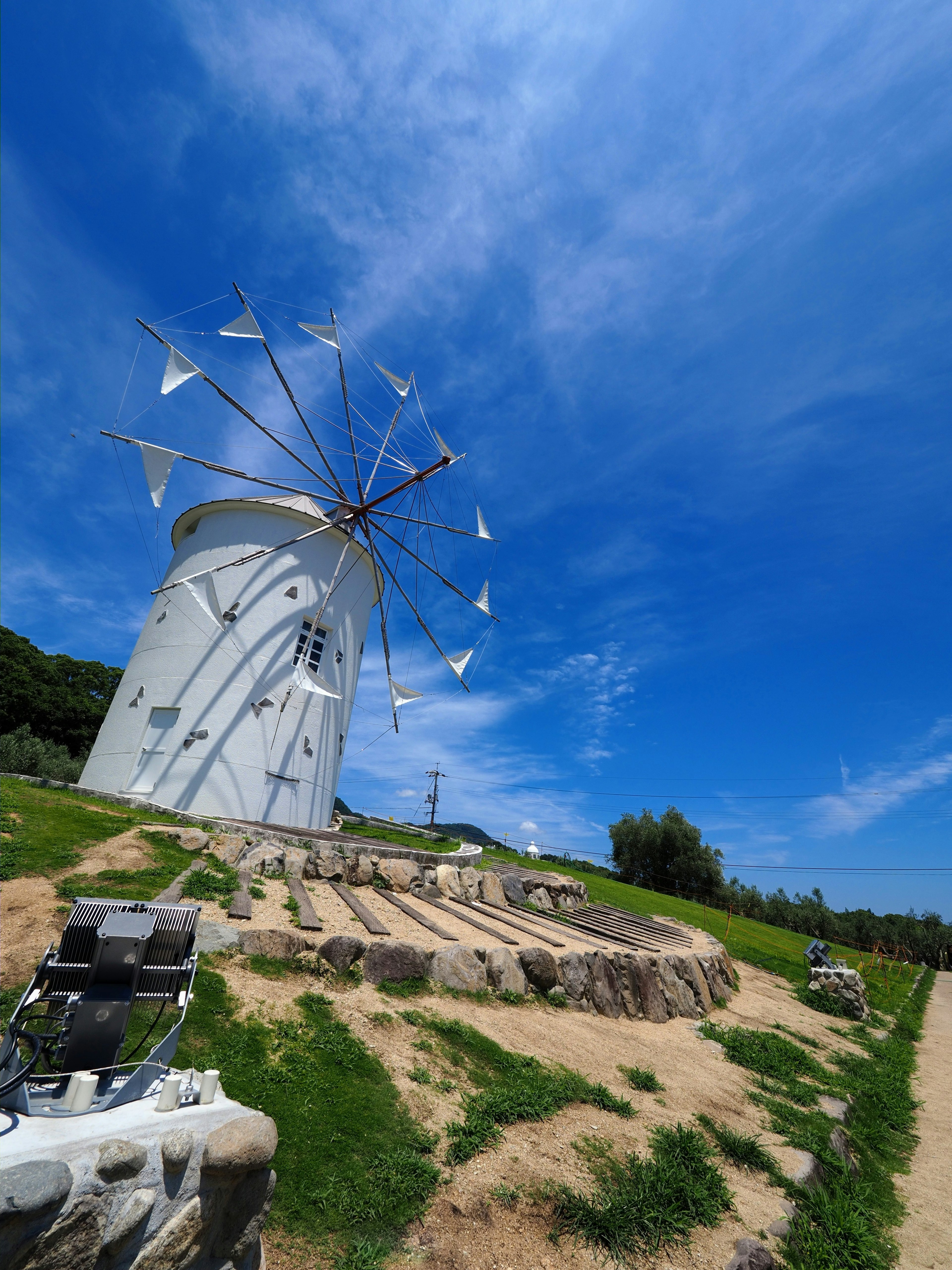 A white windmill under a blue sky with green grass