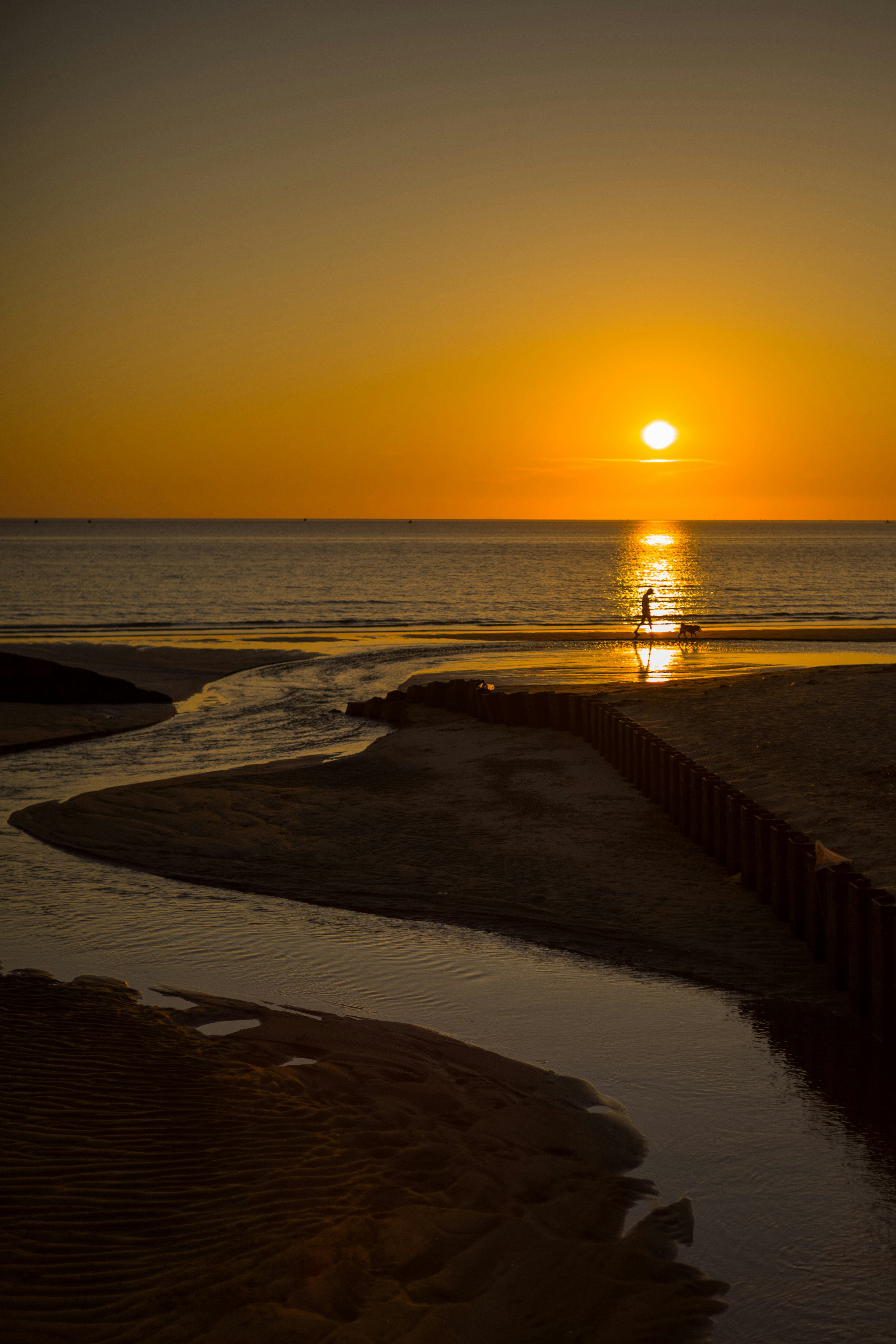 Atemberaubende Landschaft des Sonnenuntergangs über dem Ozean mit fließendem Wasser und Sandstrand