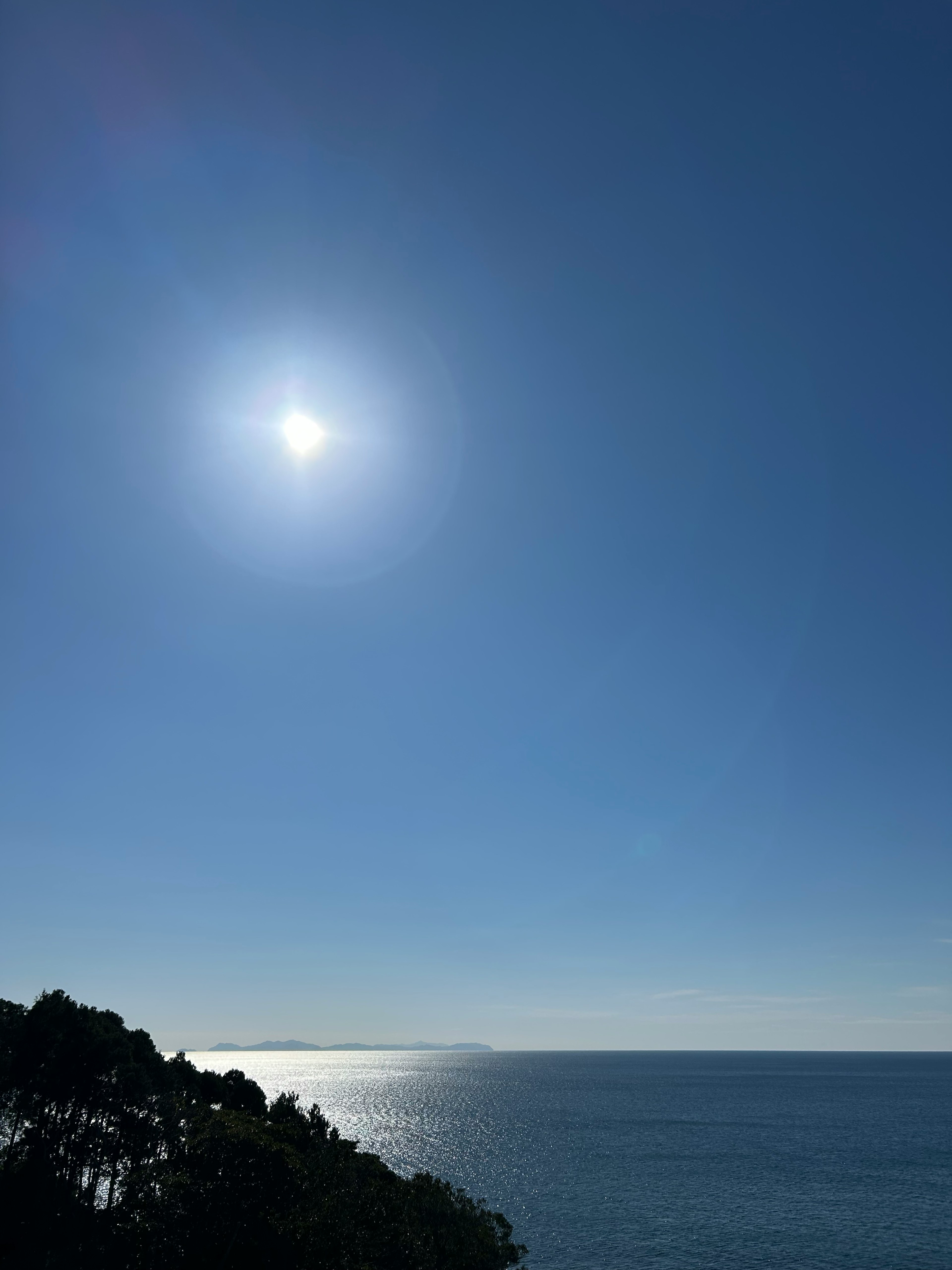 Bright sun over calm blue ocean and clear sky