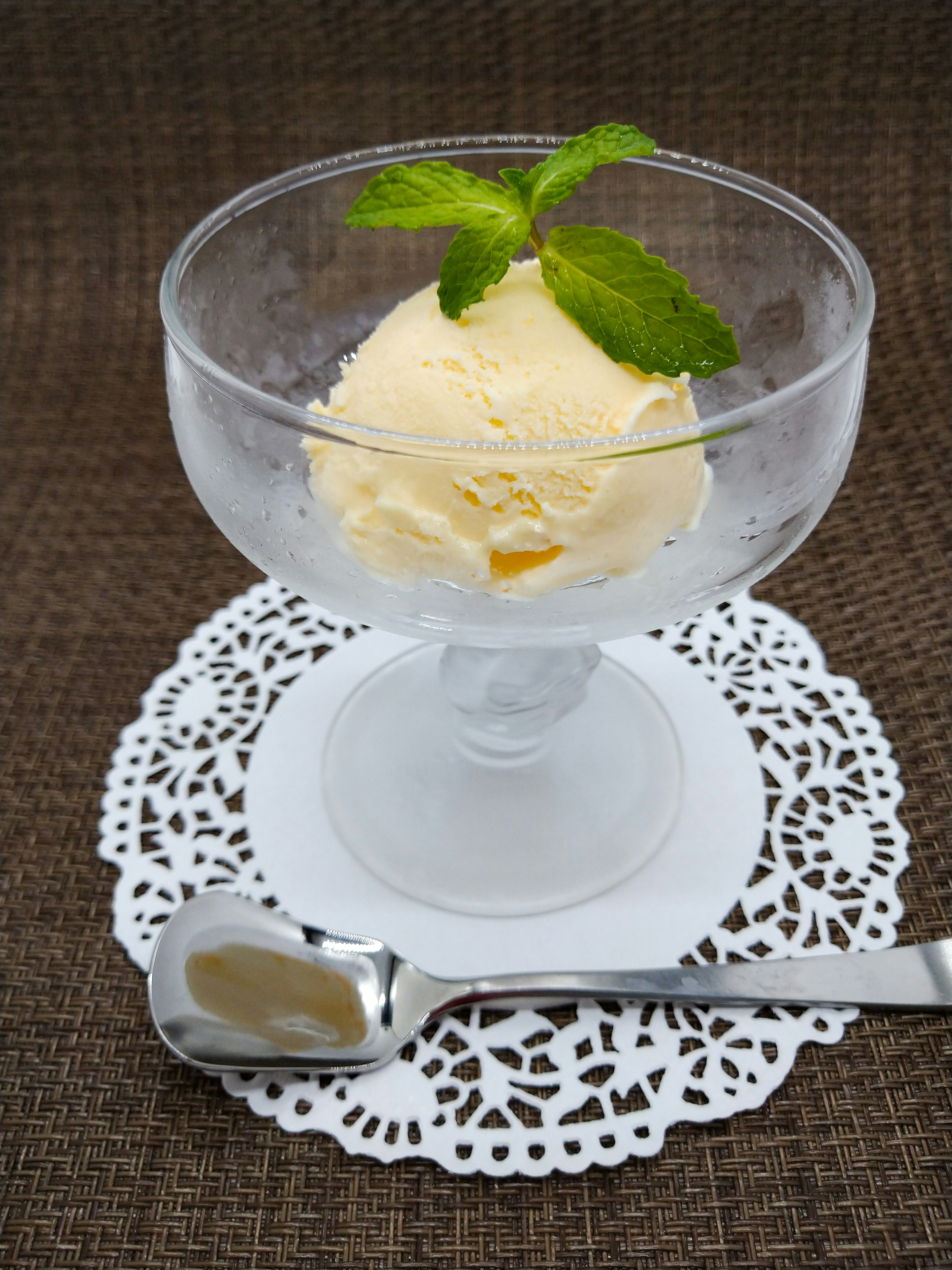 Dessert dans un bol en verre avec une boule de glace surmontée d'une feuille de menthe