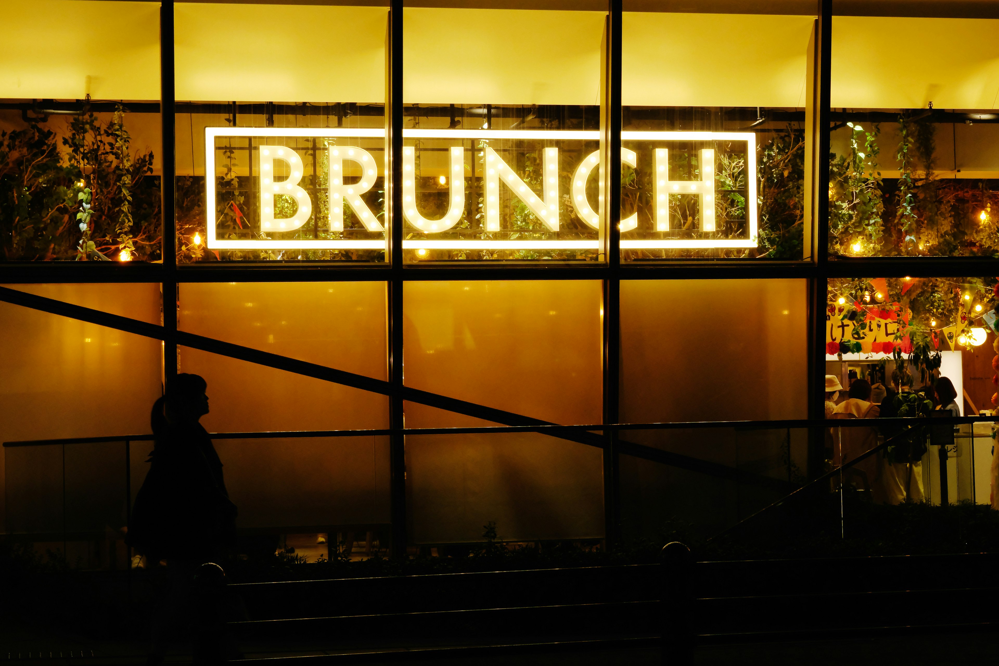 Helle Brunch-Leuchtschrift an einem Café-Fenster bei Nacht