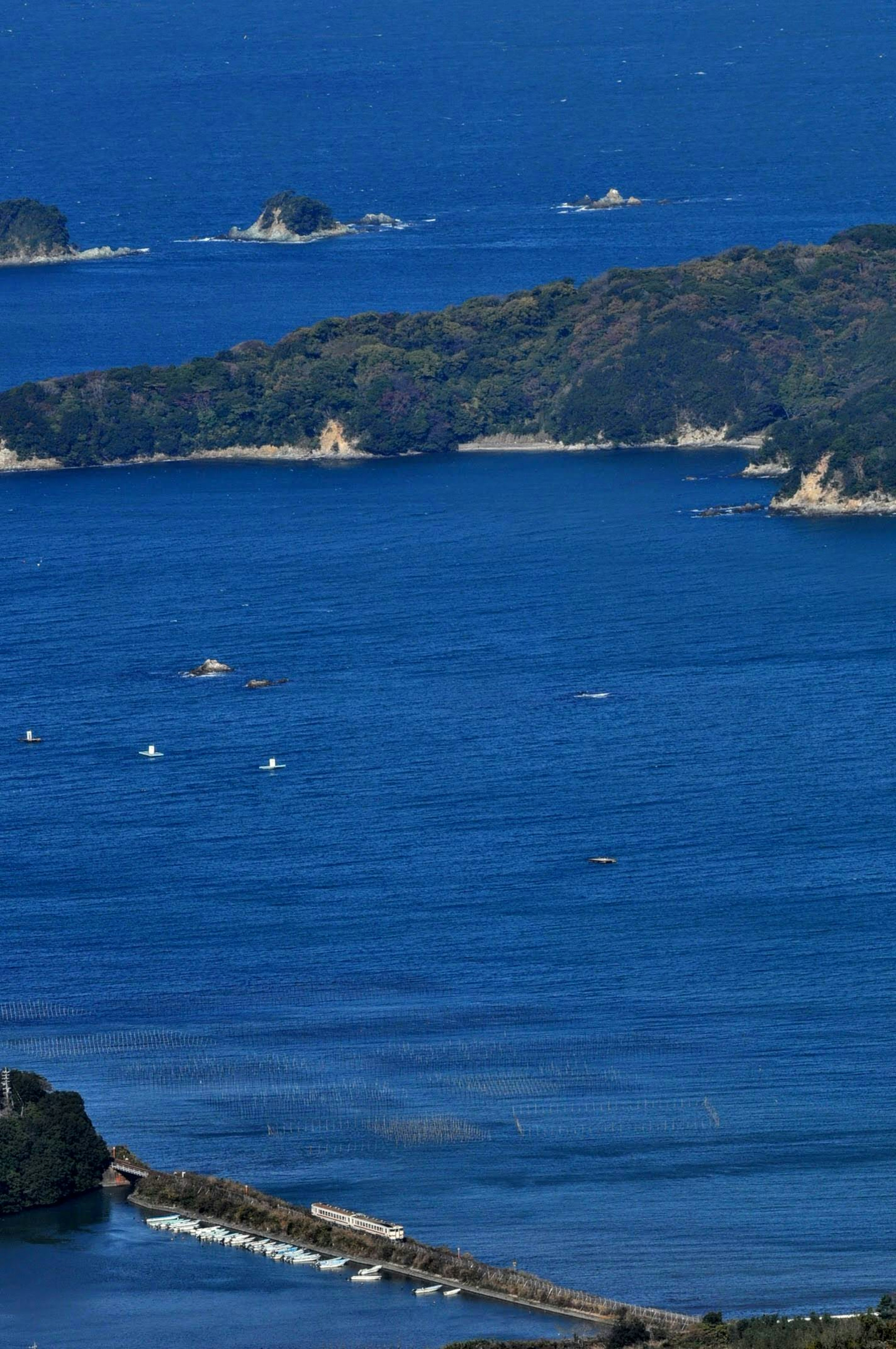 Scenic view of blue sea with small islands and boats scattered