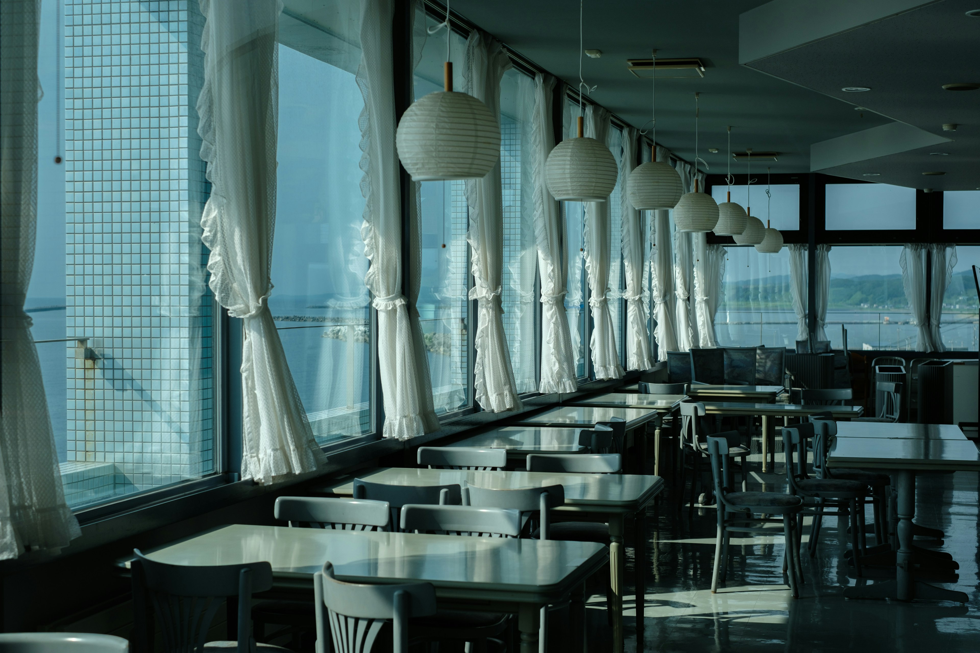 Interior of a cafe with tables and chairs by bright windows