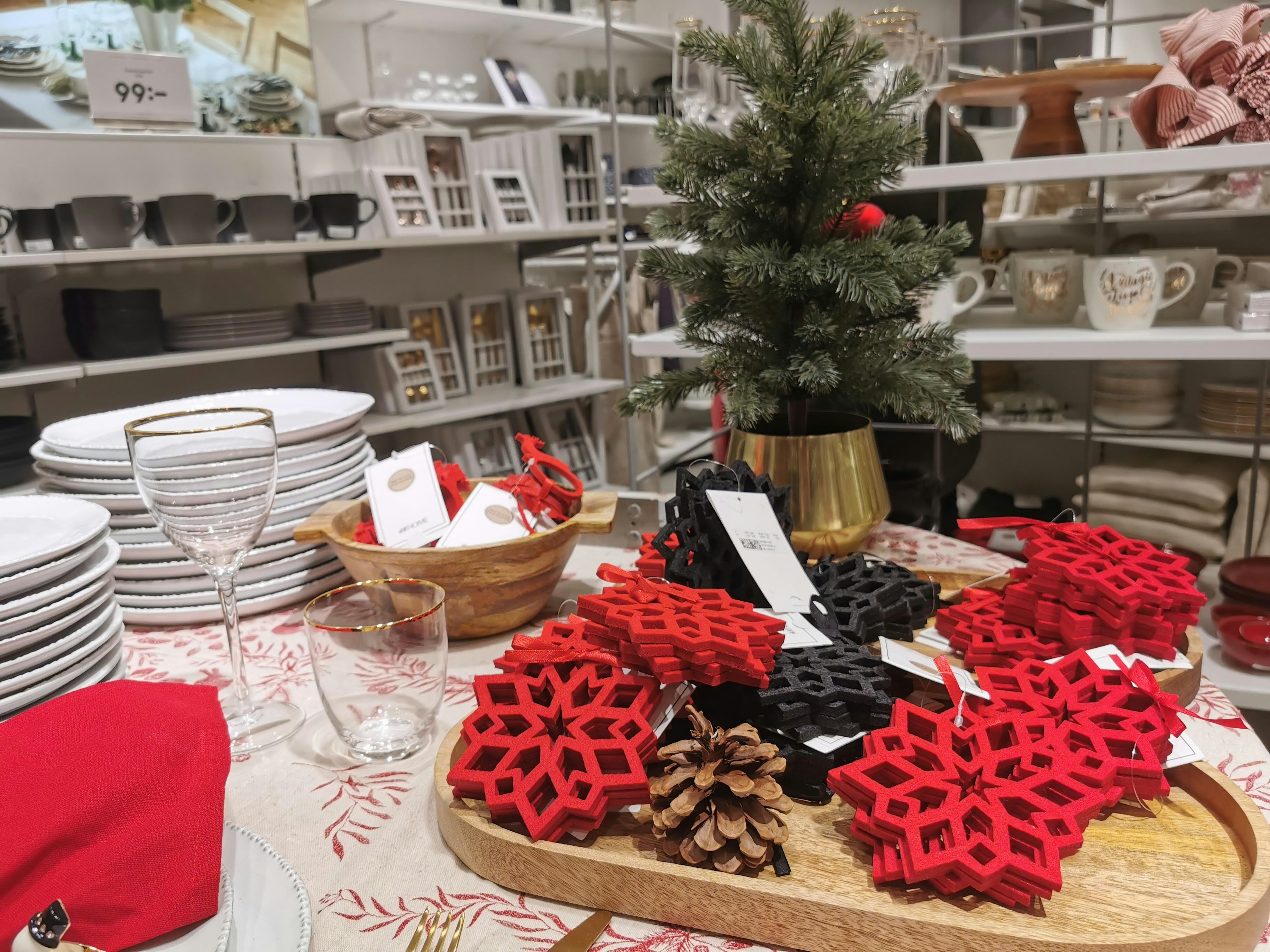 Imagen que presenta una decoración de mesa navideña con posavasos en forma de copo de nieve rojos y negros y piñas