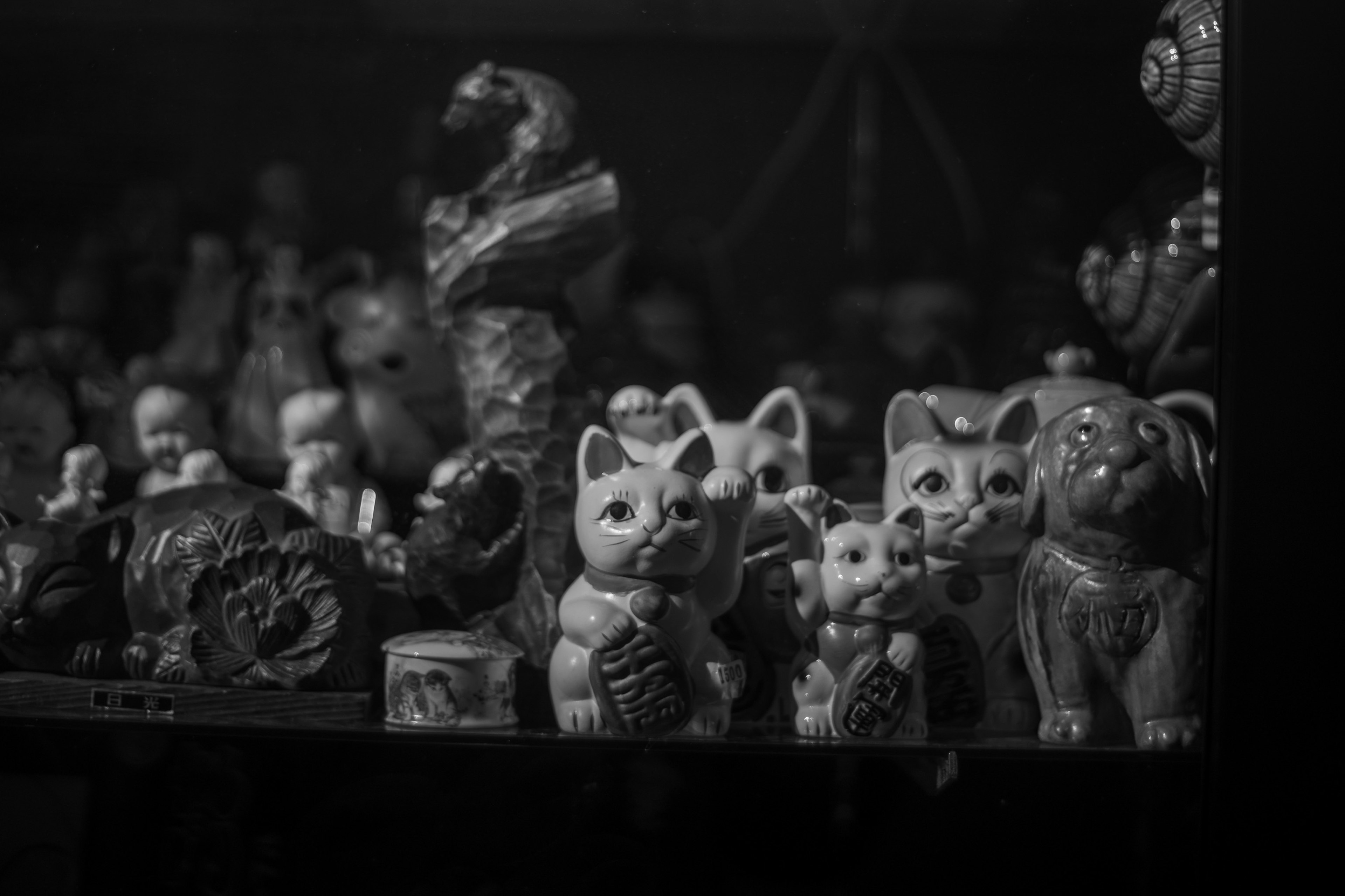 Una colección de gatos de cerámica en blanco y negro y esculturas en una estantería