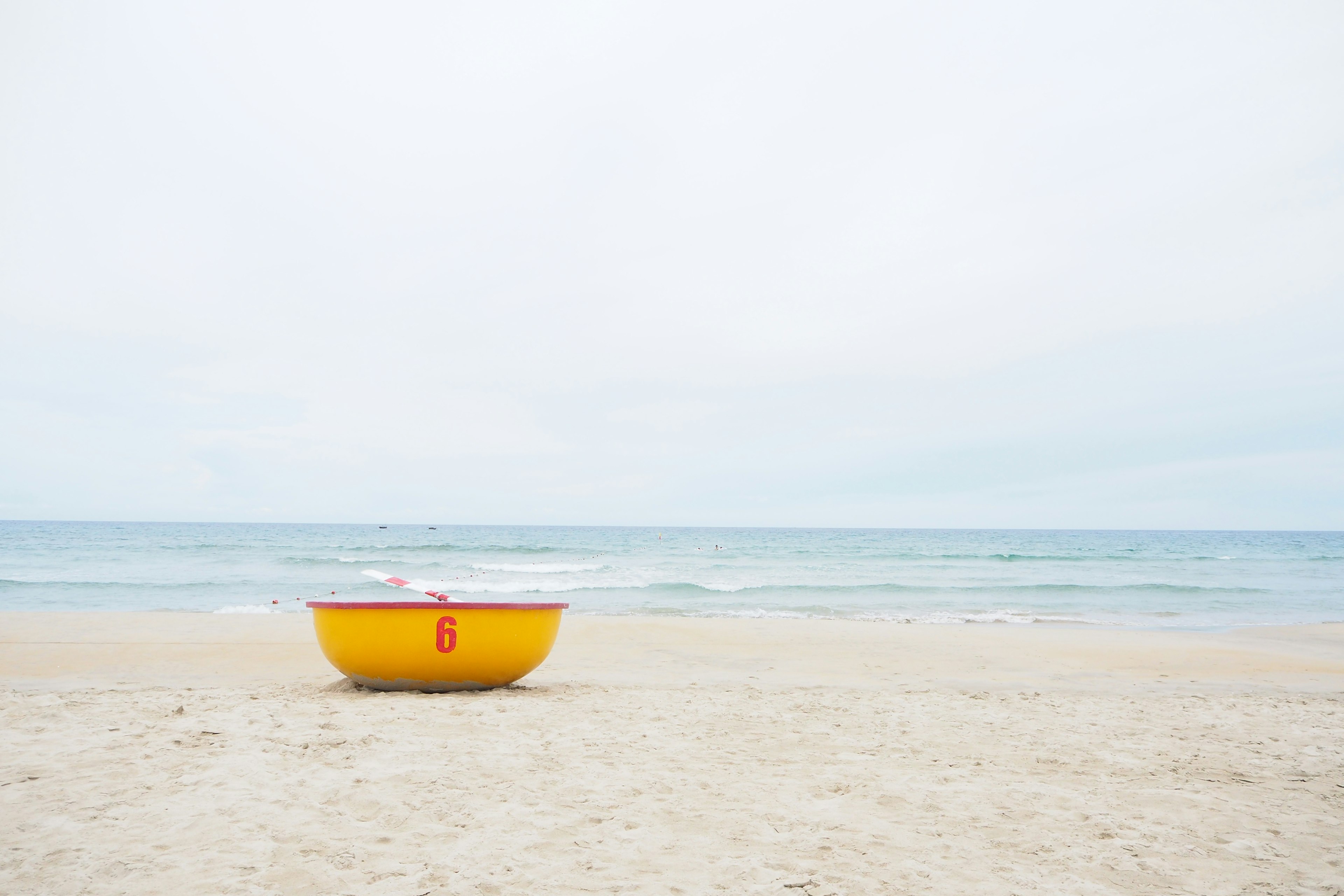 Ein auffälliges gelbes Boot an einem Strand mit bewölktem Himmel