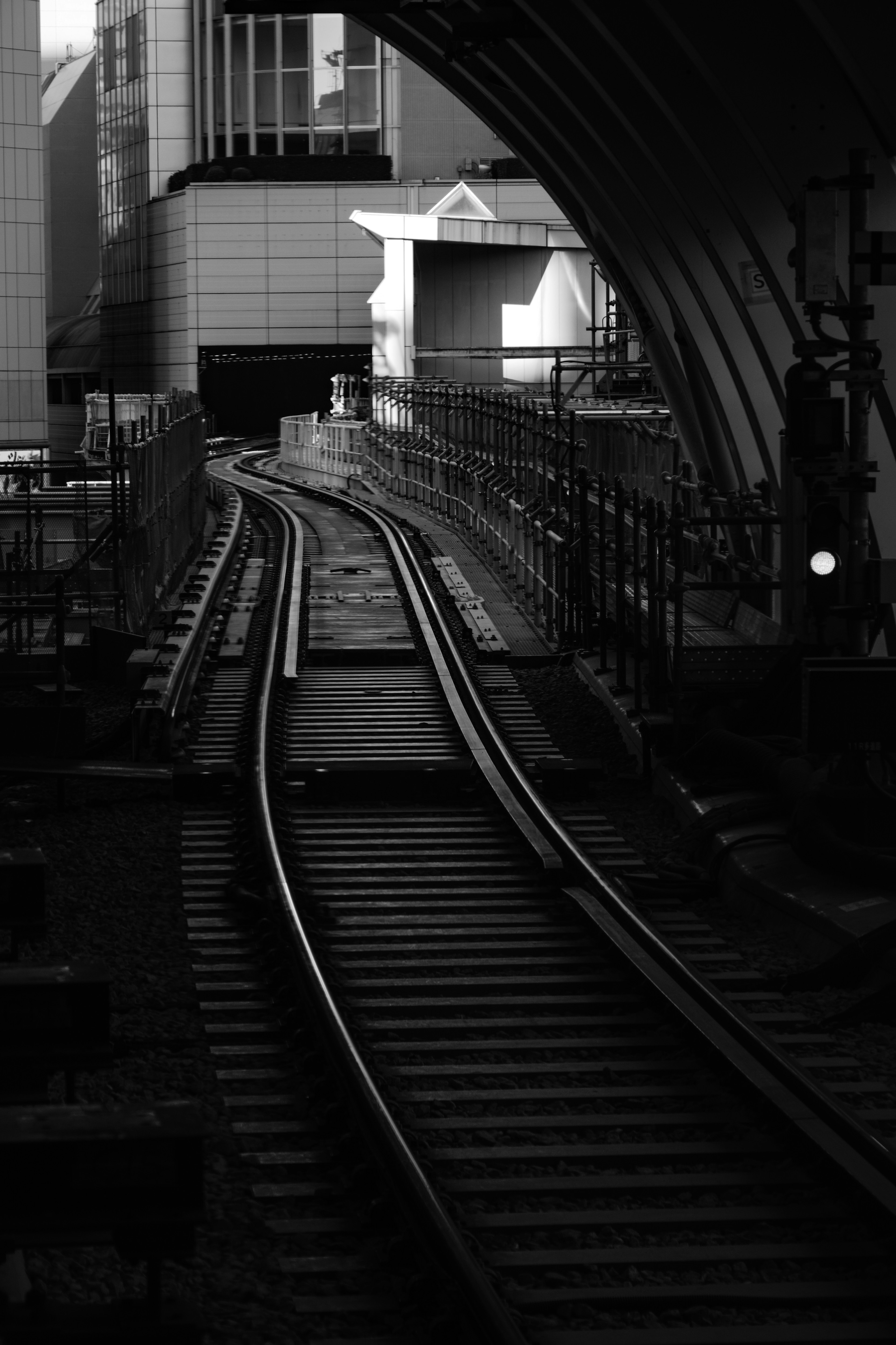 Gekrümmte Gleise in einem dunklen Tunnel mit umliegenden Gebäuden