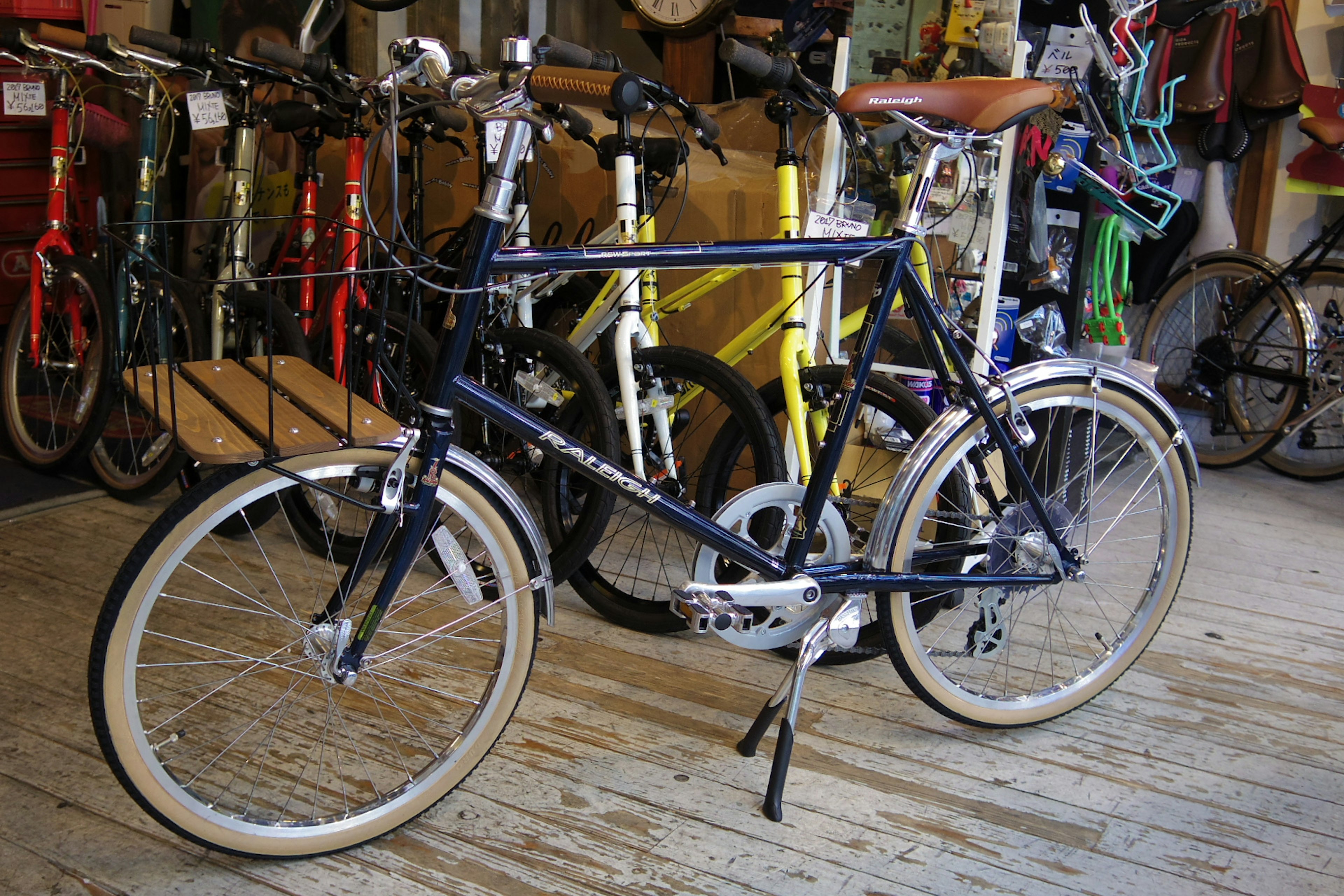 Un vélo bleu sur un sol en bois entouré d'autres vélos