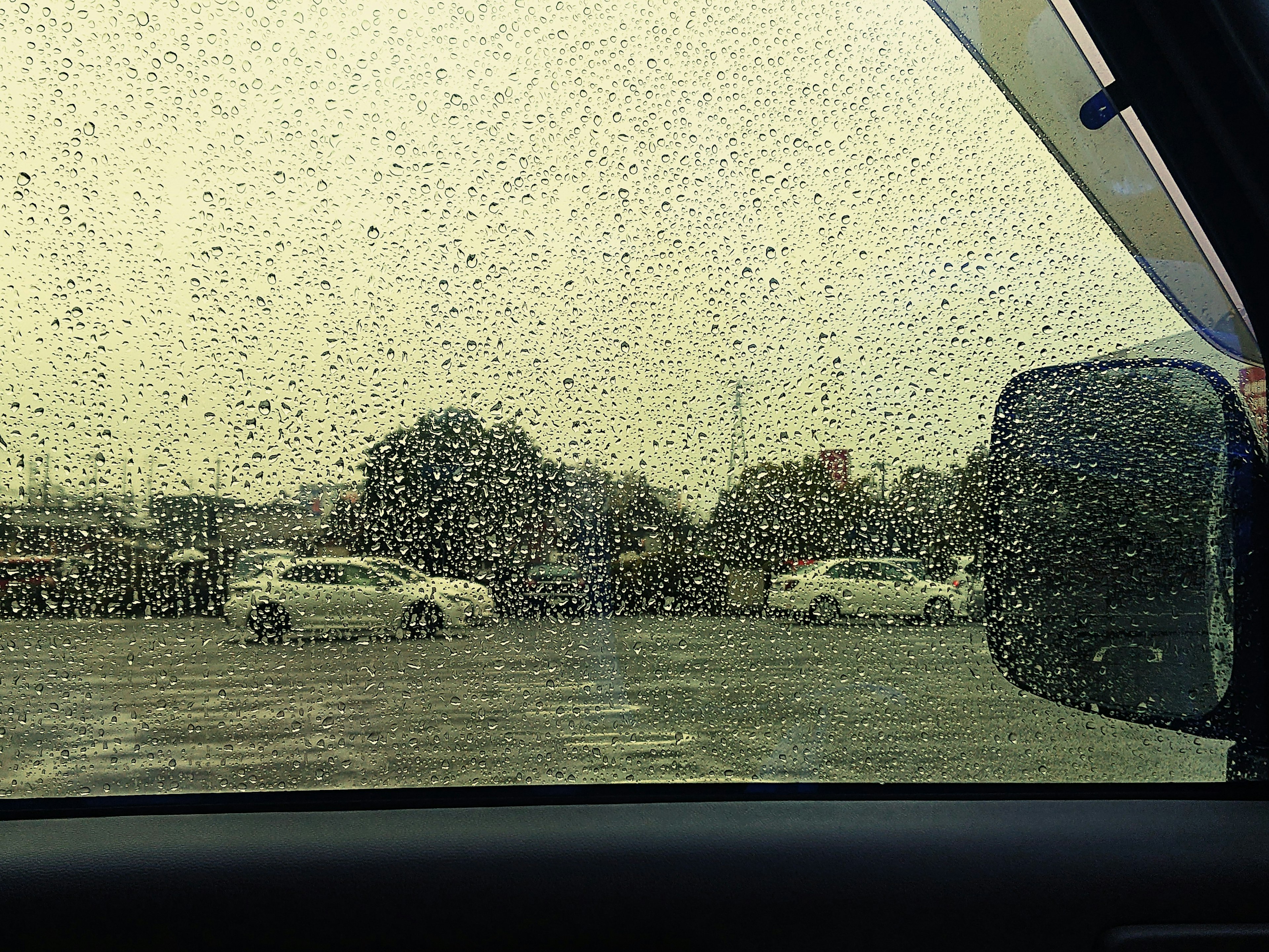 View of a parking lot through a rain-speckled car window