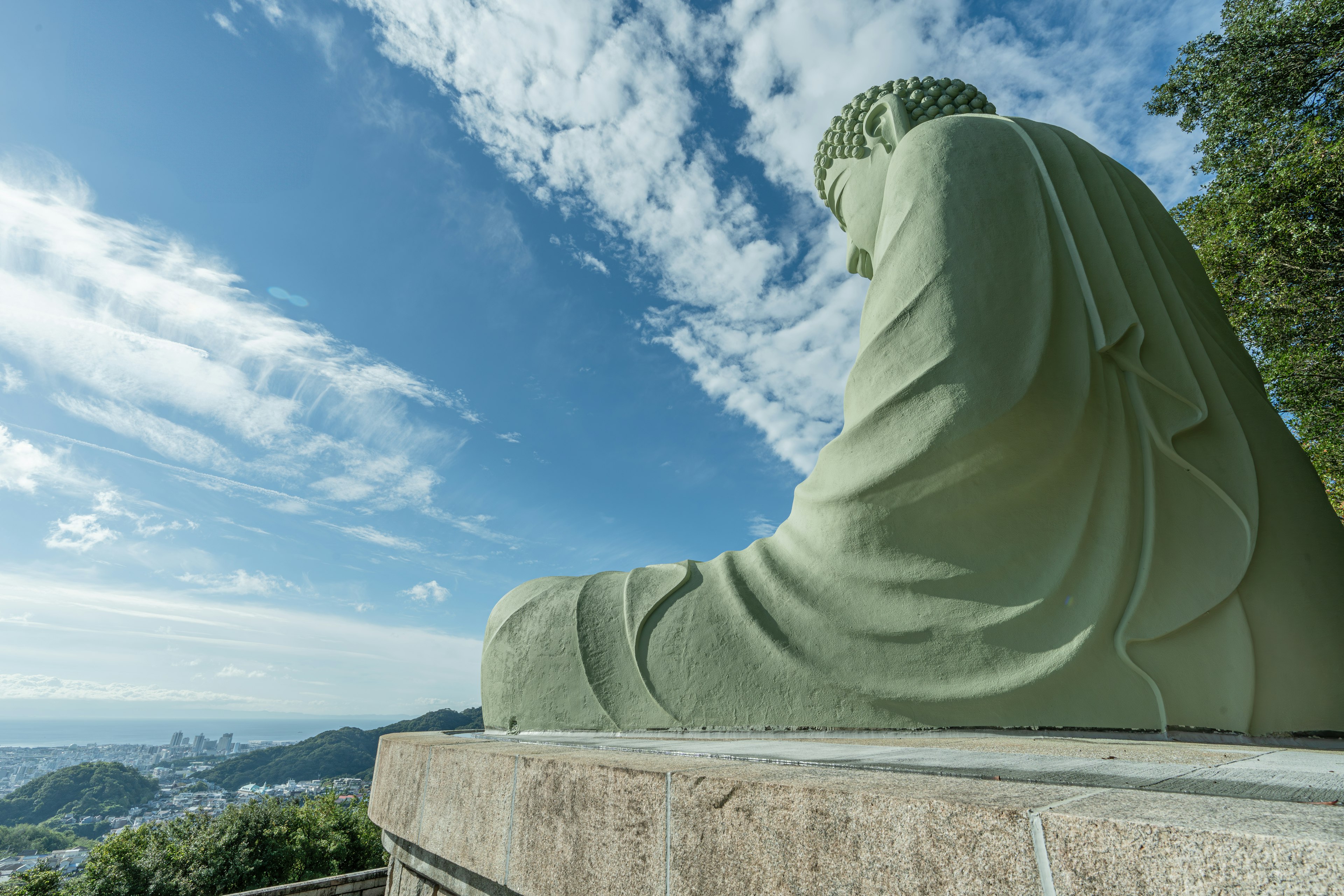 Grande statue de Bouddha assise sous un ciel bleu avec des nuages