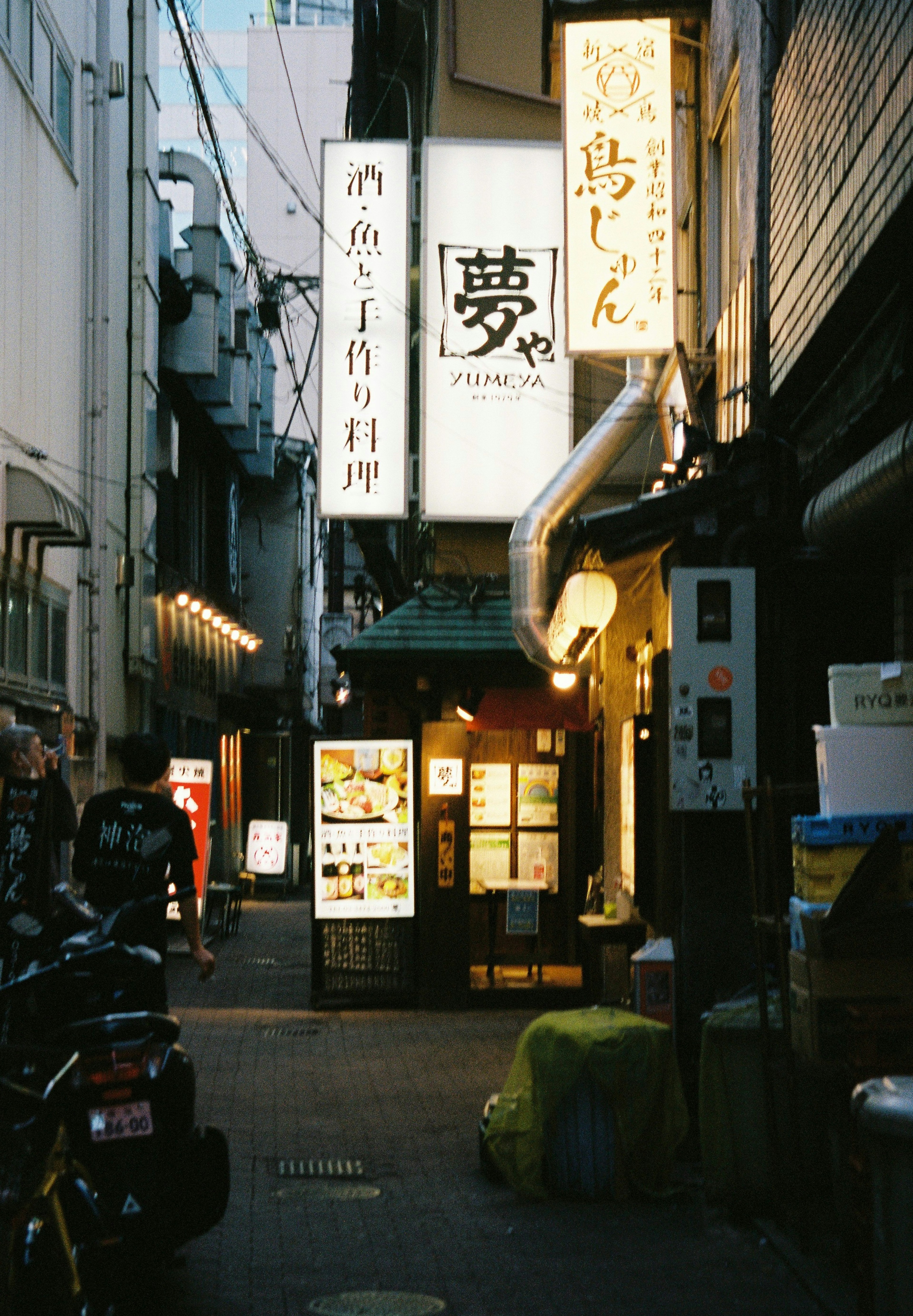 Exterior de un restaurante japonés en un callejón estrecho con letreros