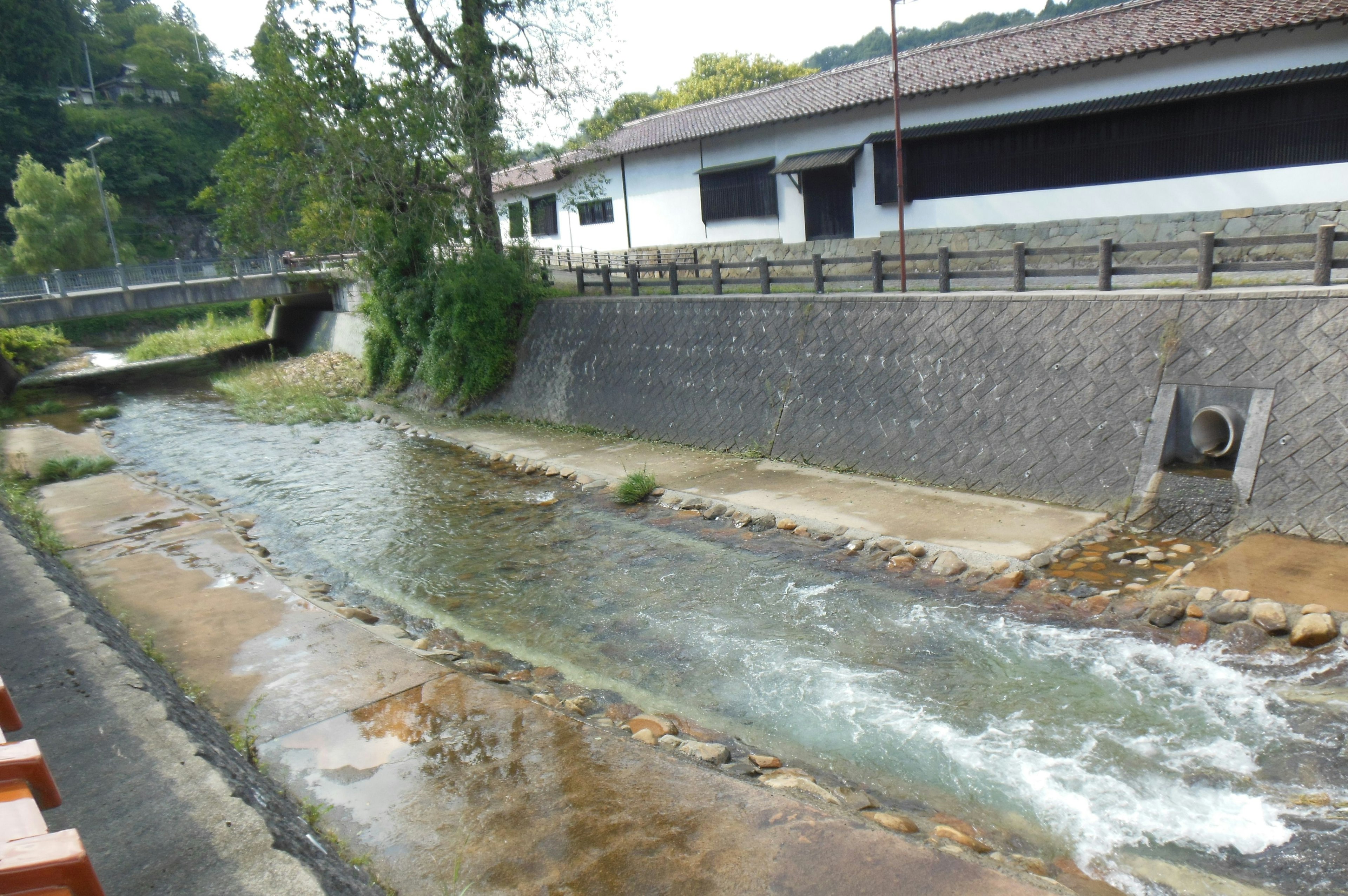 Eine Landschaft mit einem Fluss und einem Steinwehr mit einem alten Gebäude im Hintergrund