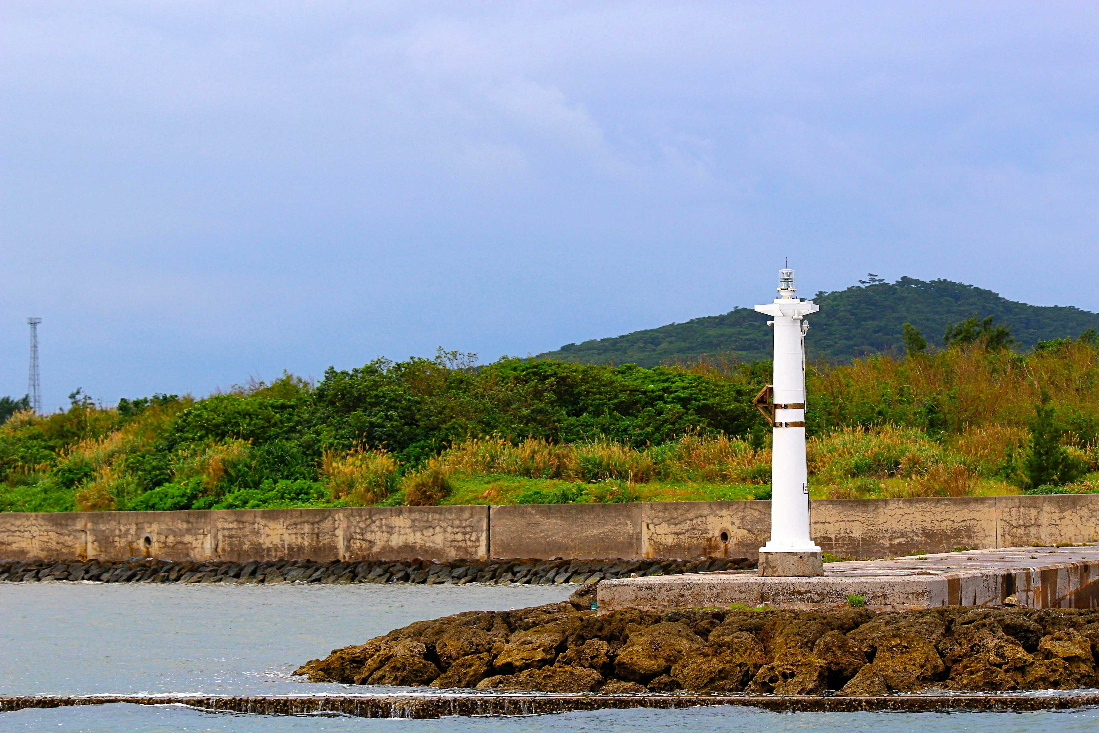 海岸に立つ白い灯台と緑の丘の風景