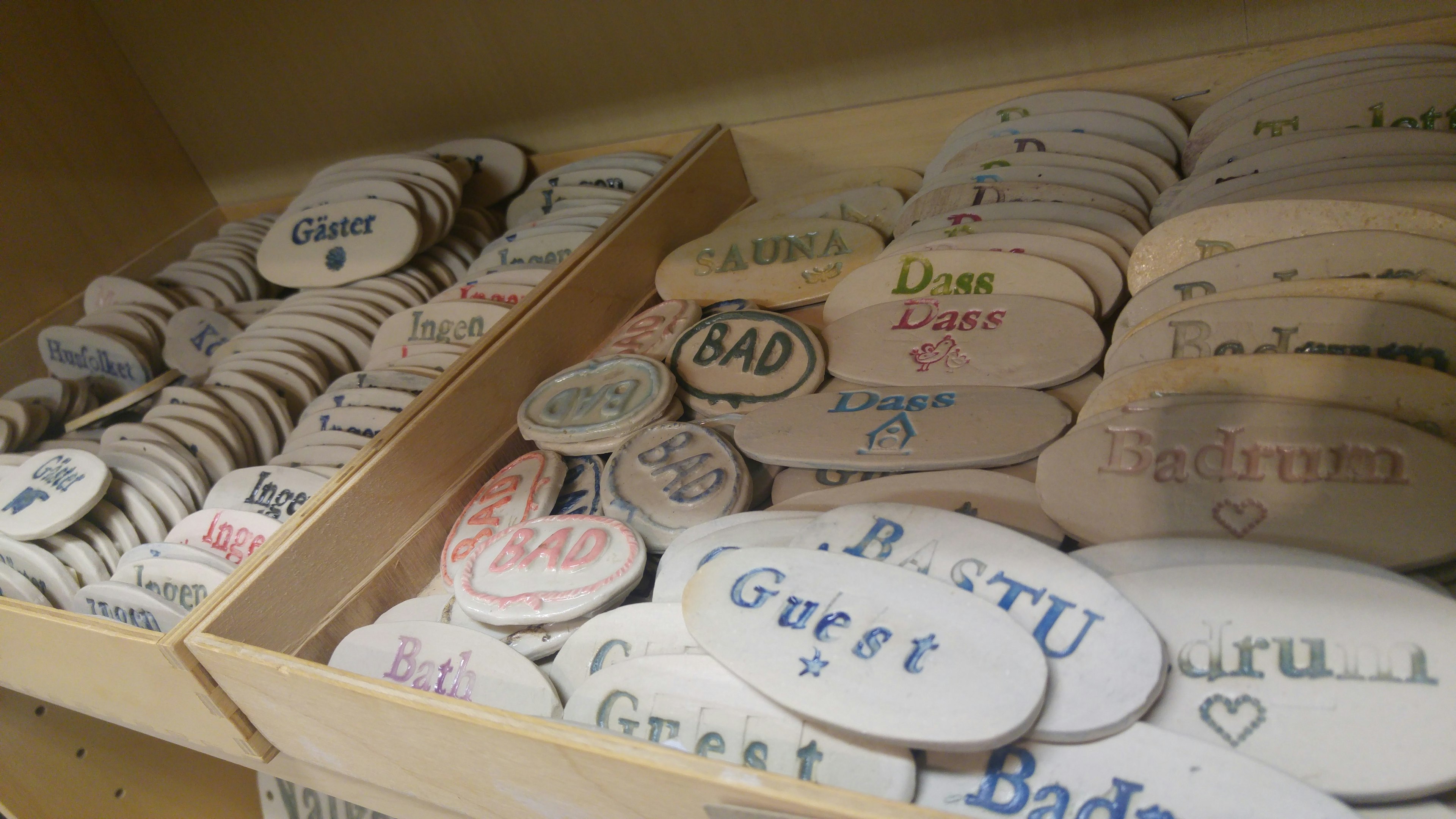 Various names and messages painted on wooden coasters arranged in a box