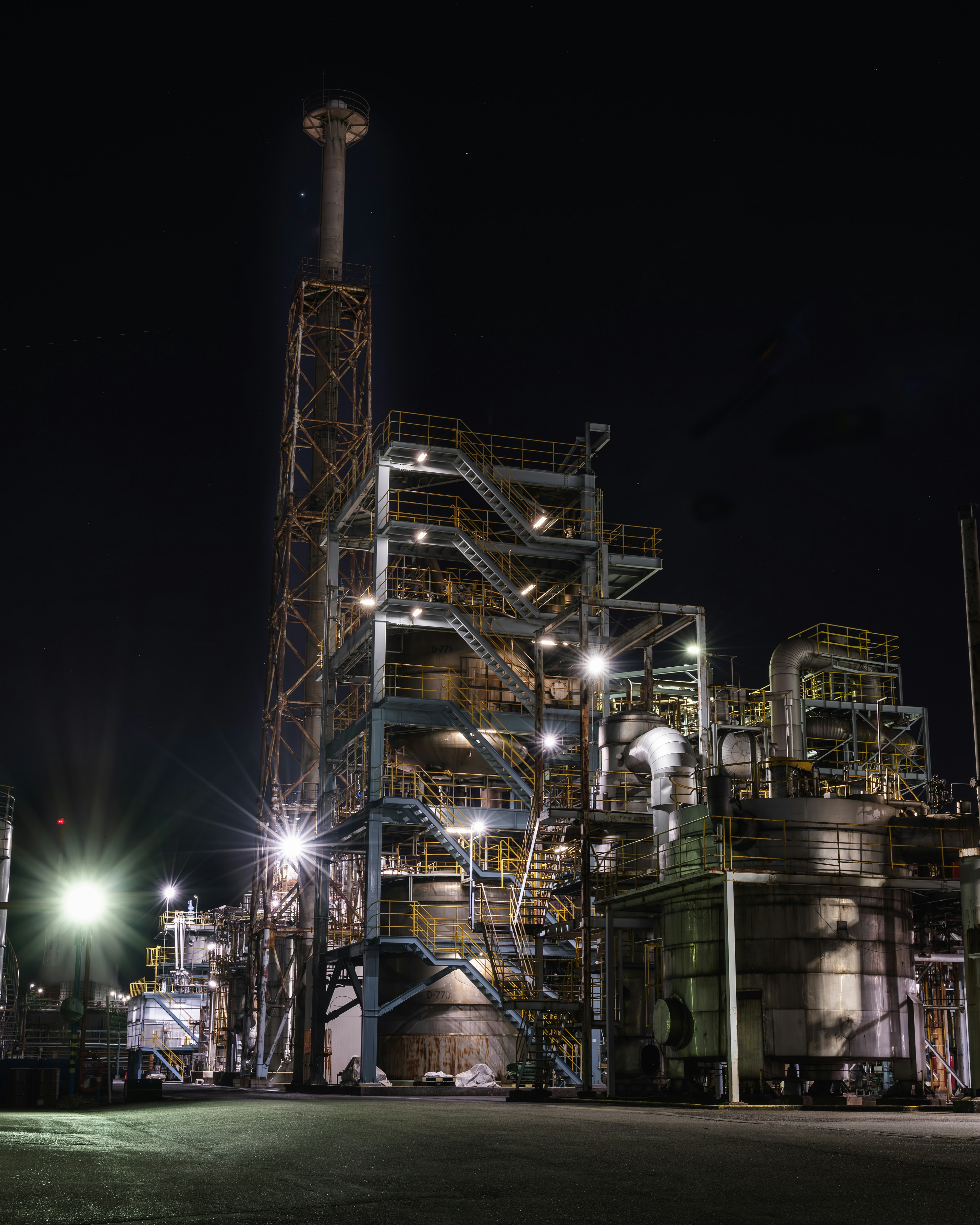 Planta industrial nocturna con luces brillantes y estructuras complejas