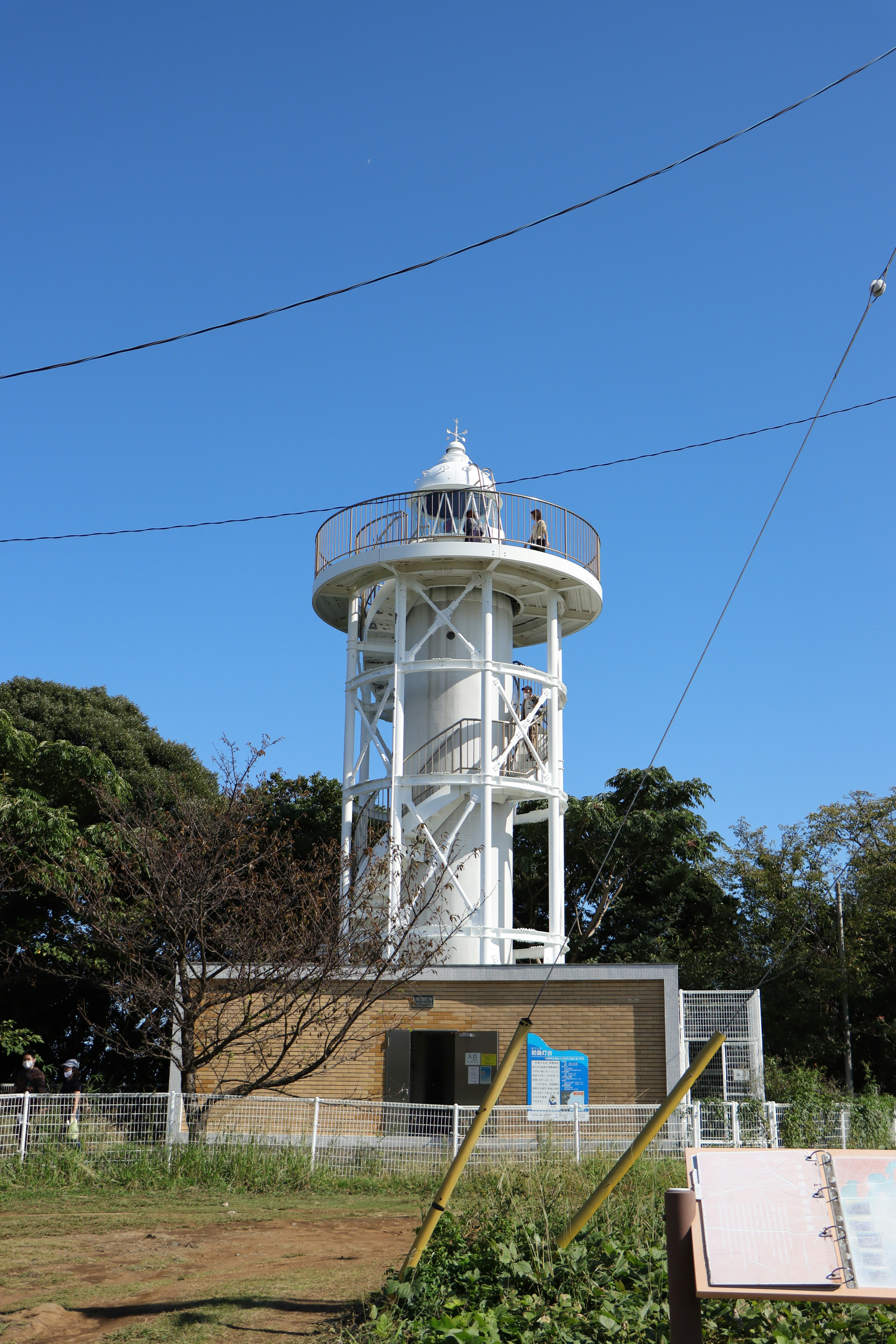 A white water tower standing amidst greenery under a clear blue sky