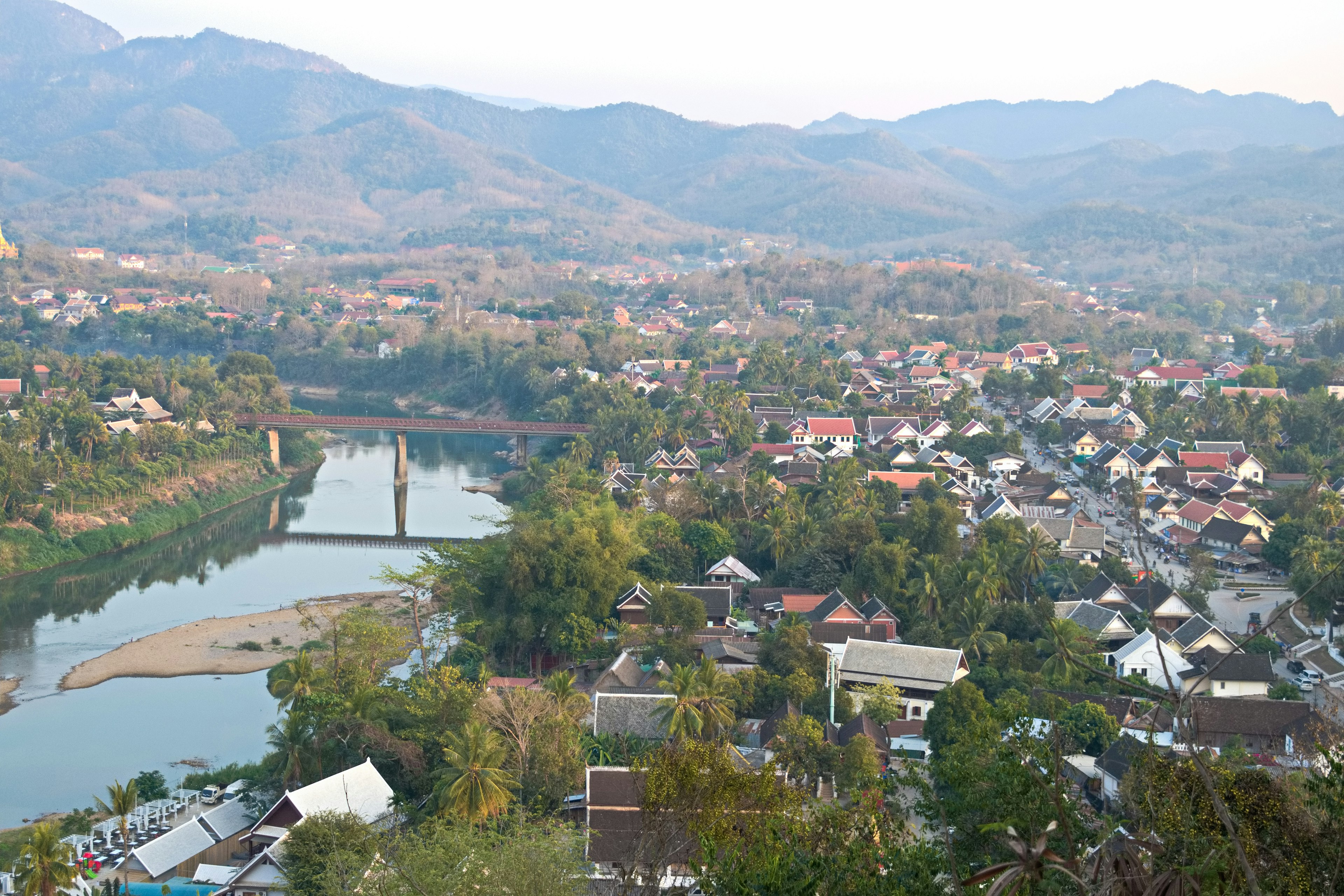 Vista panoramica di un villaggio circondato da montagne con un fiume e un ponte