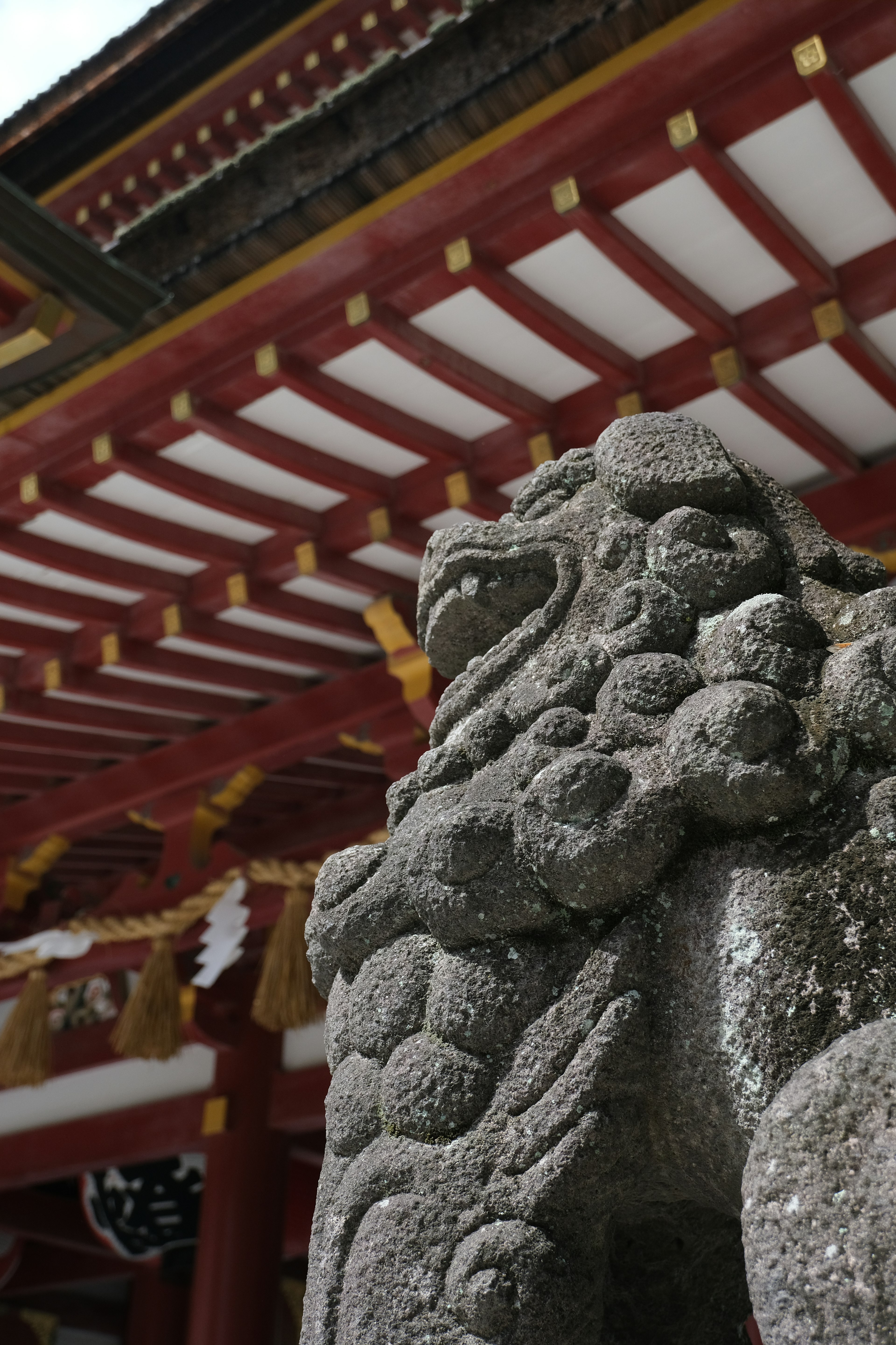 Stone guardian lion sculpture at a red-roofed temple