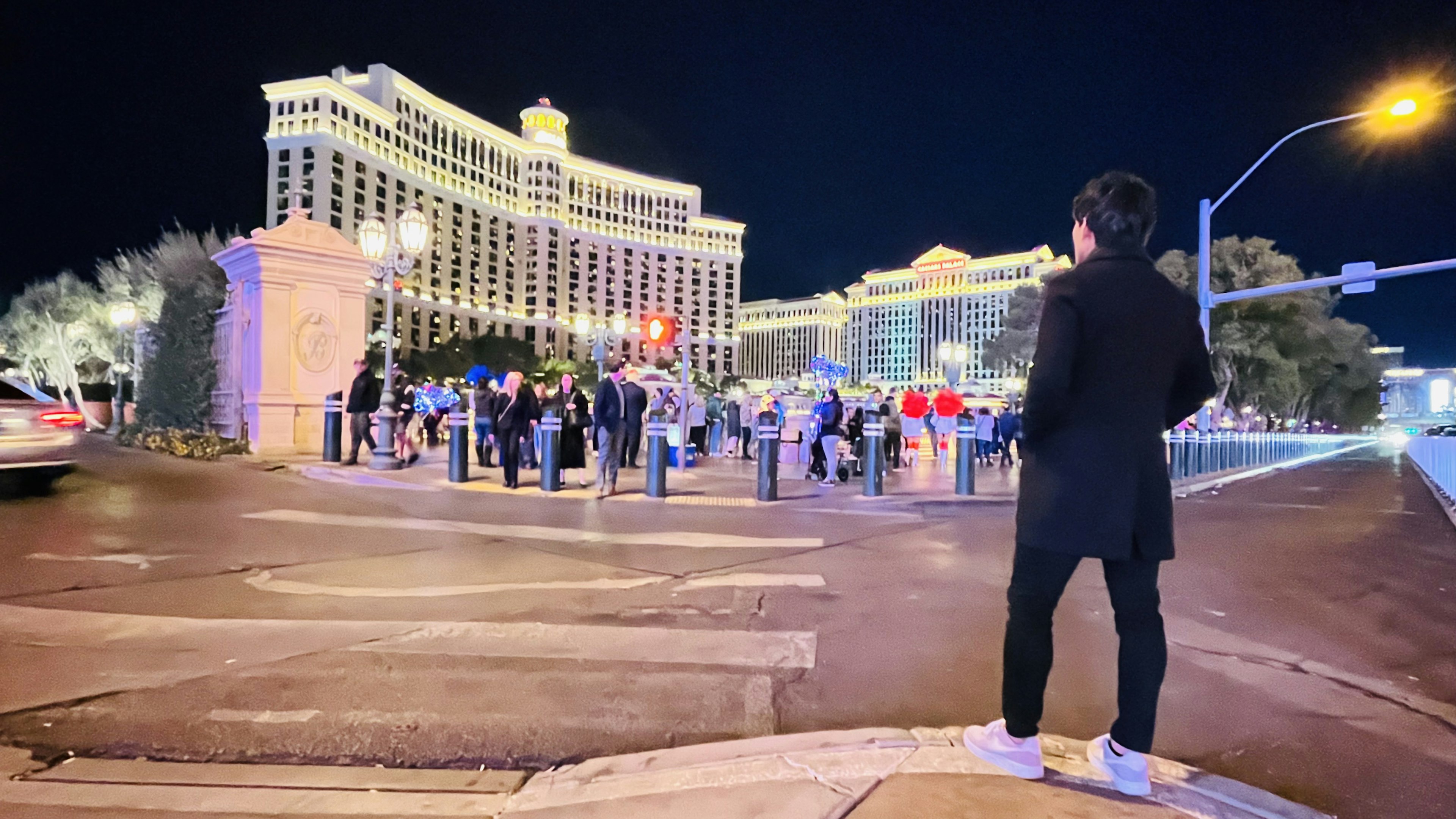 Eine Person steht nachts in Las Vegas mit dem Bellagio Hotel im Hintergrund und einer versammelten Menge