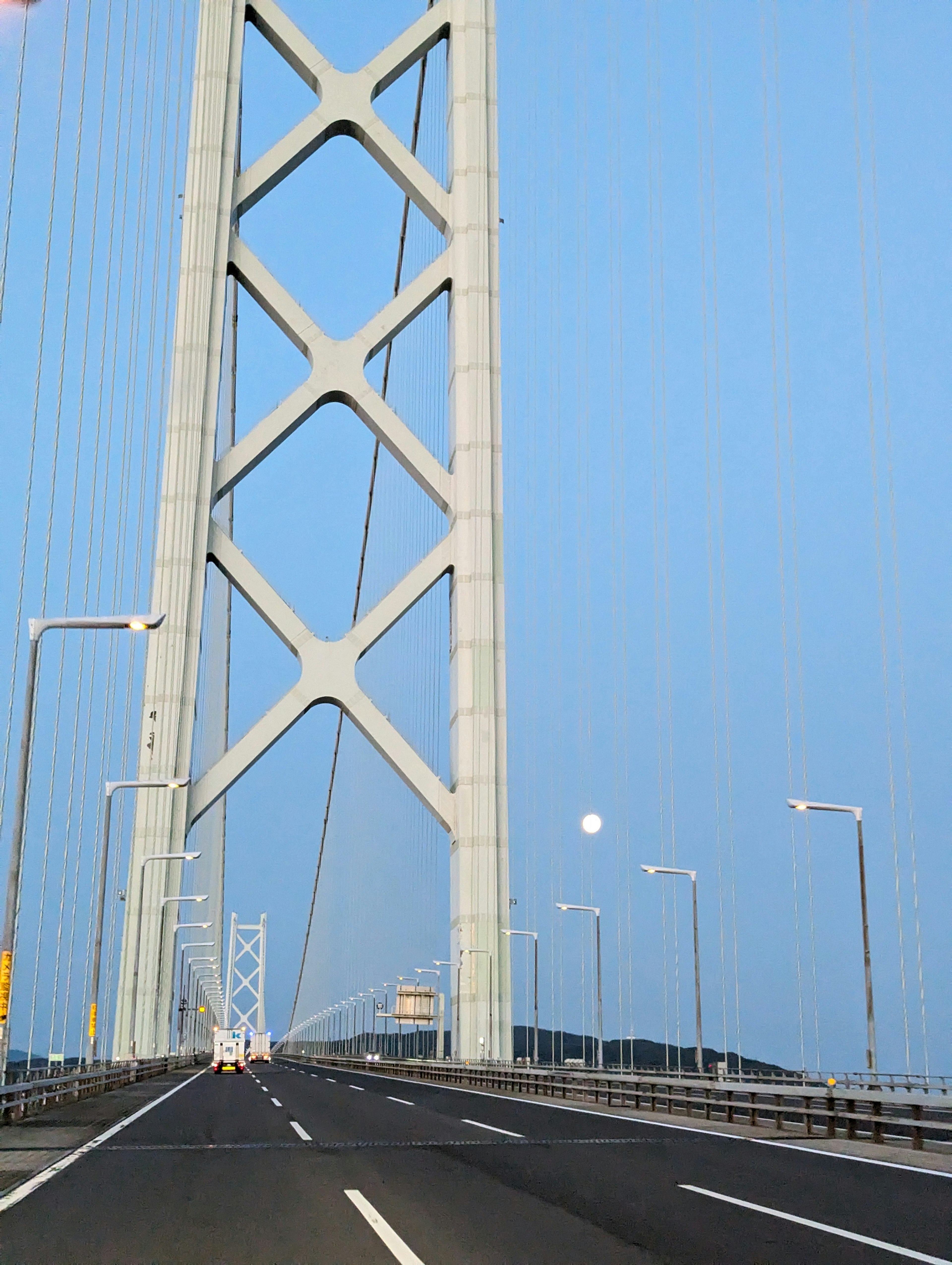 Bridge support structure under a blue sky with the moon visible