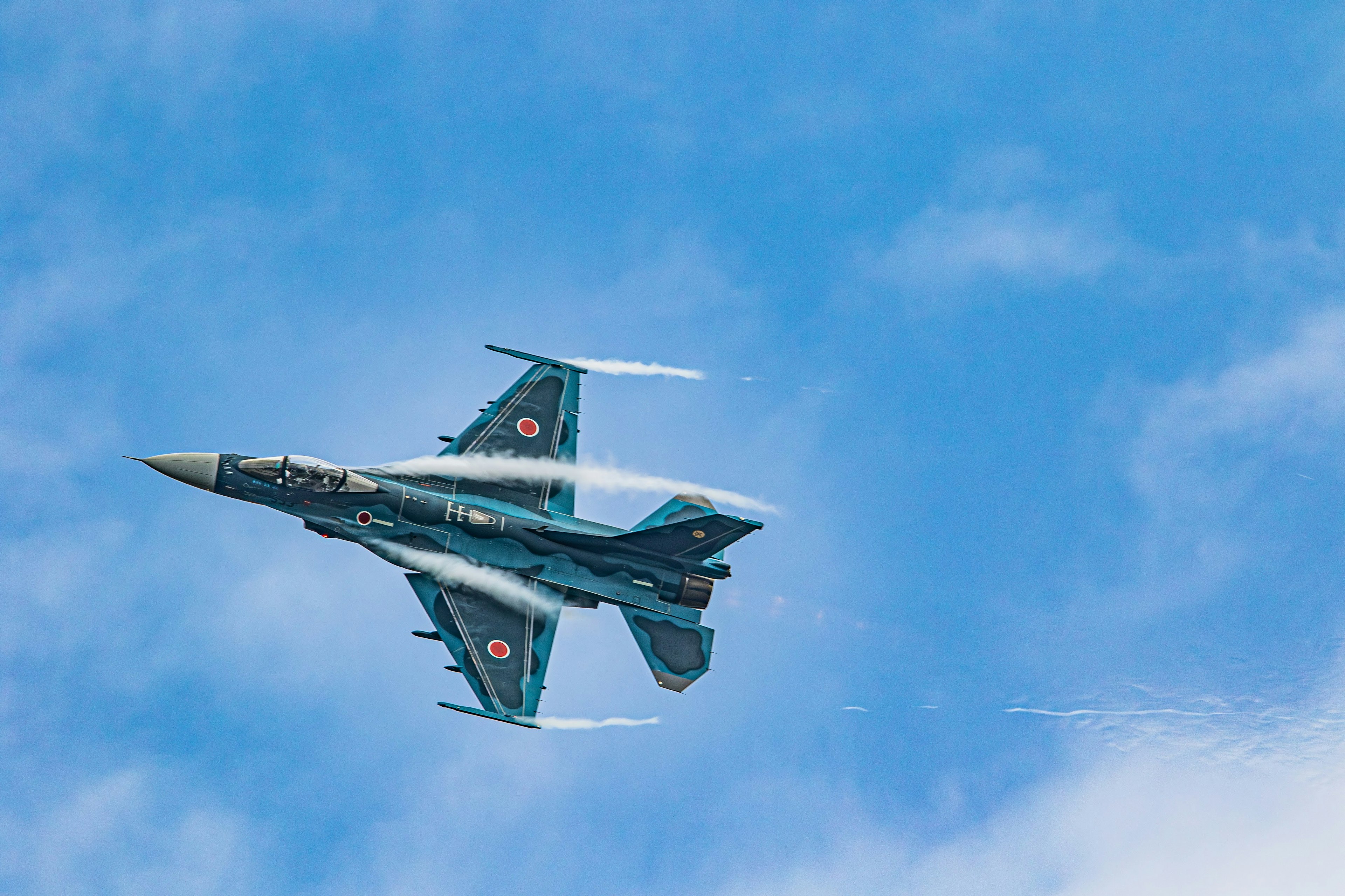 Un avion de chasse effectuant un virage serré contre un ciel bleu