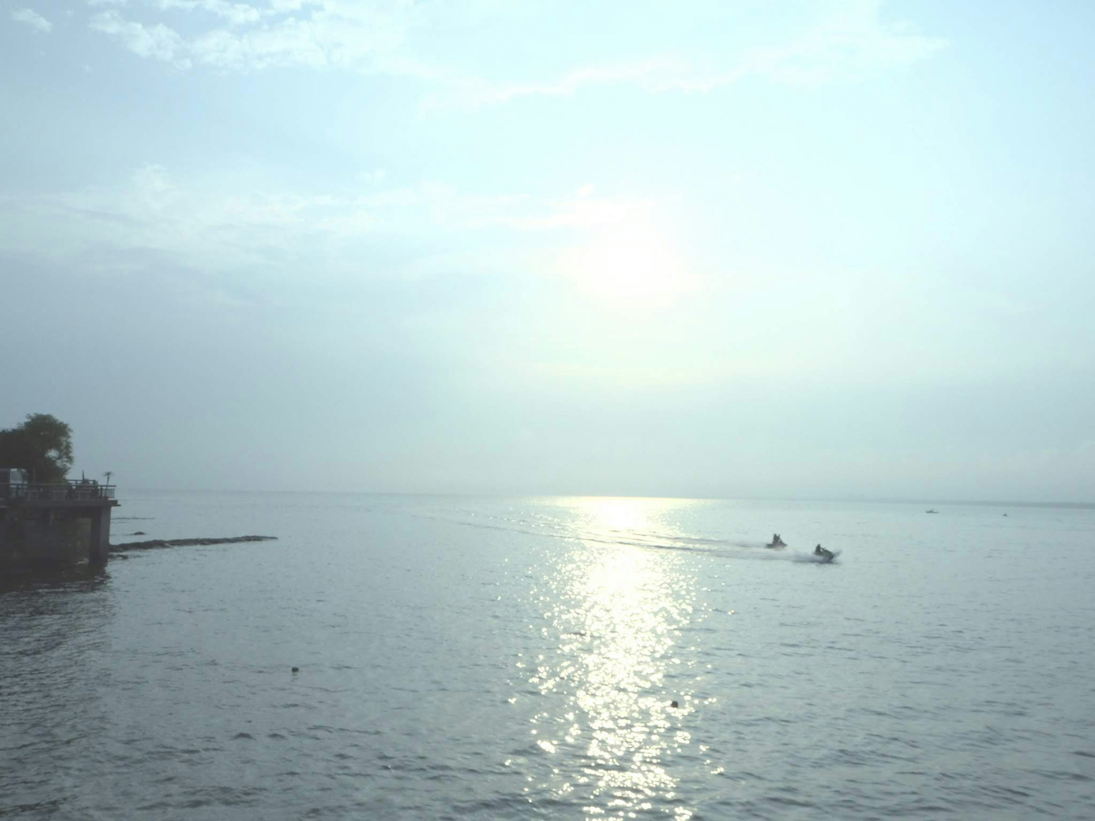 Agua tranquila reflejando el amanecer con siluetas de barcos de pesca