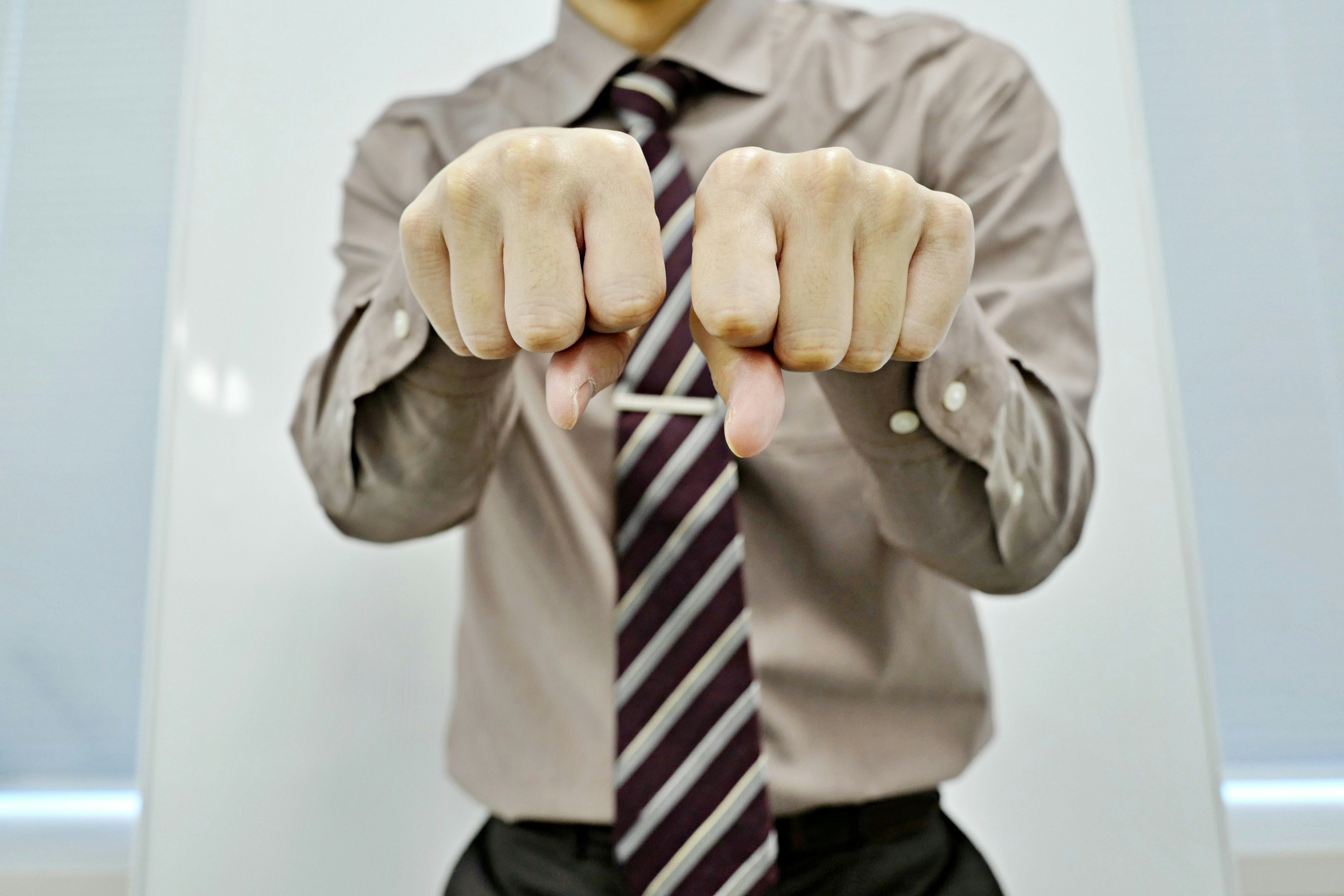 A man in a button-down shirt and tie holding his fists up in front