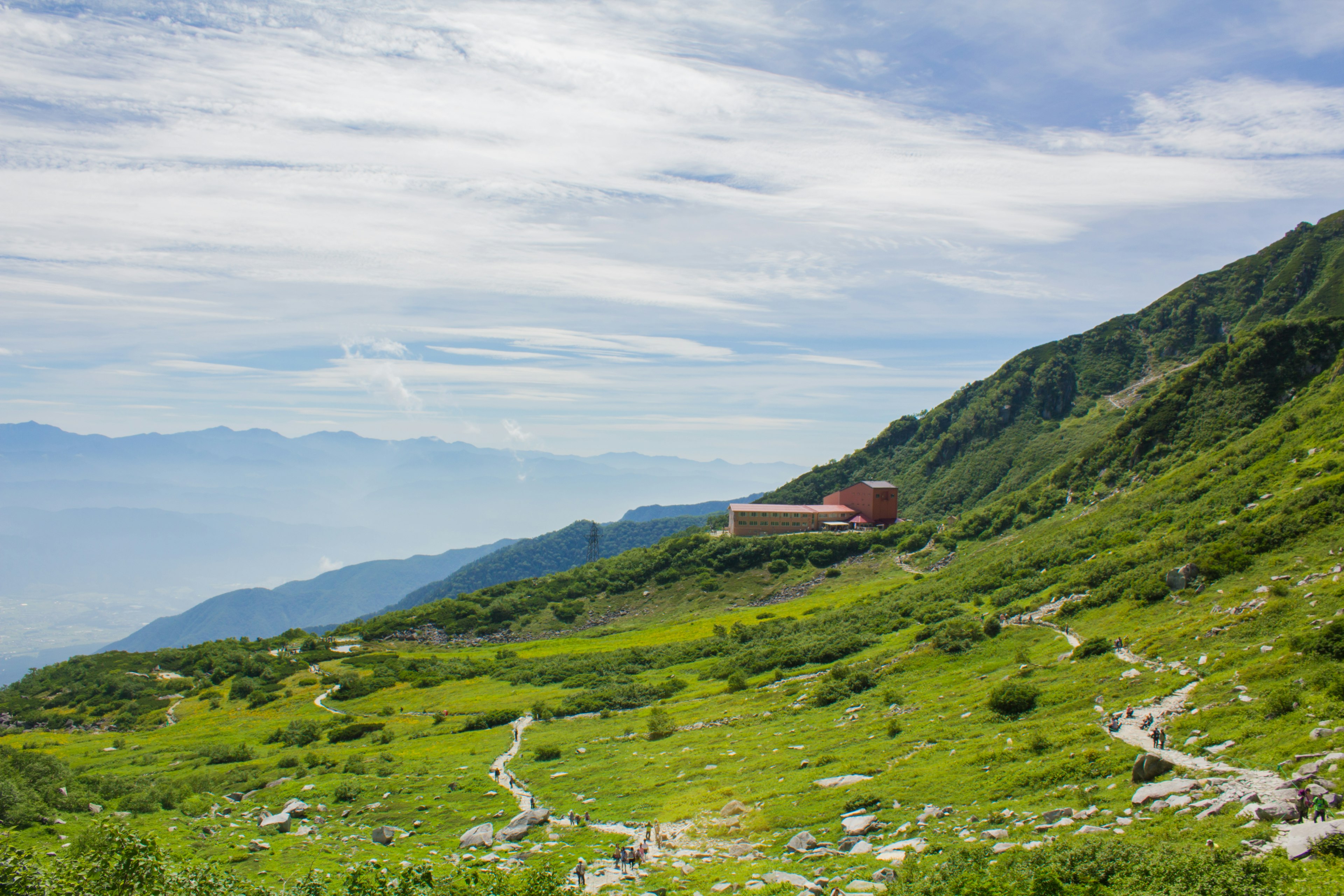 Paesaggio montano verdeggiante con un edificio rosso