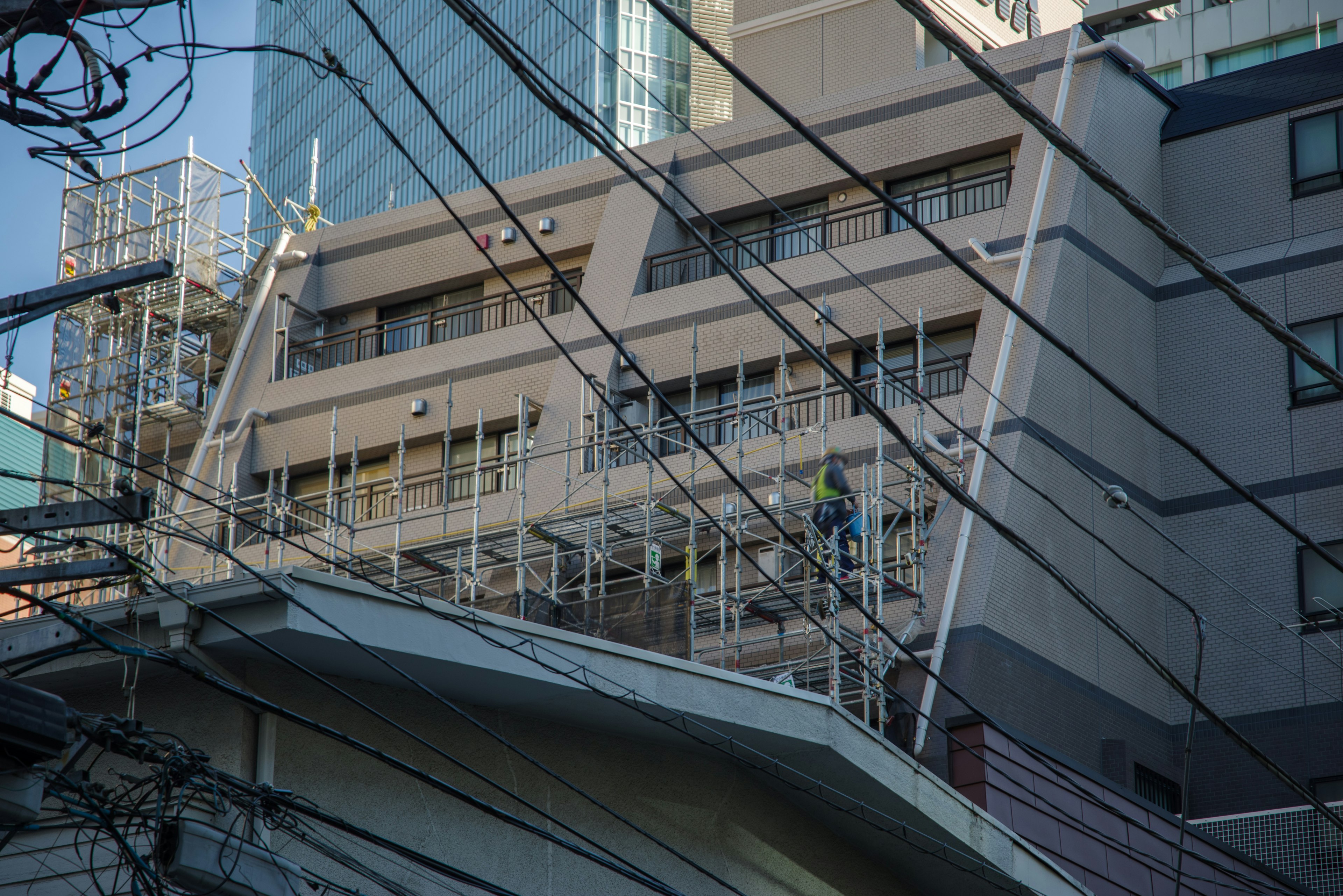 高層ビルの近くで工事中の建物と電線が見える