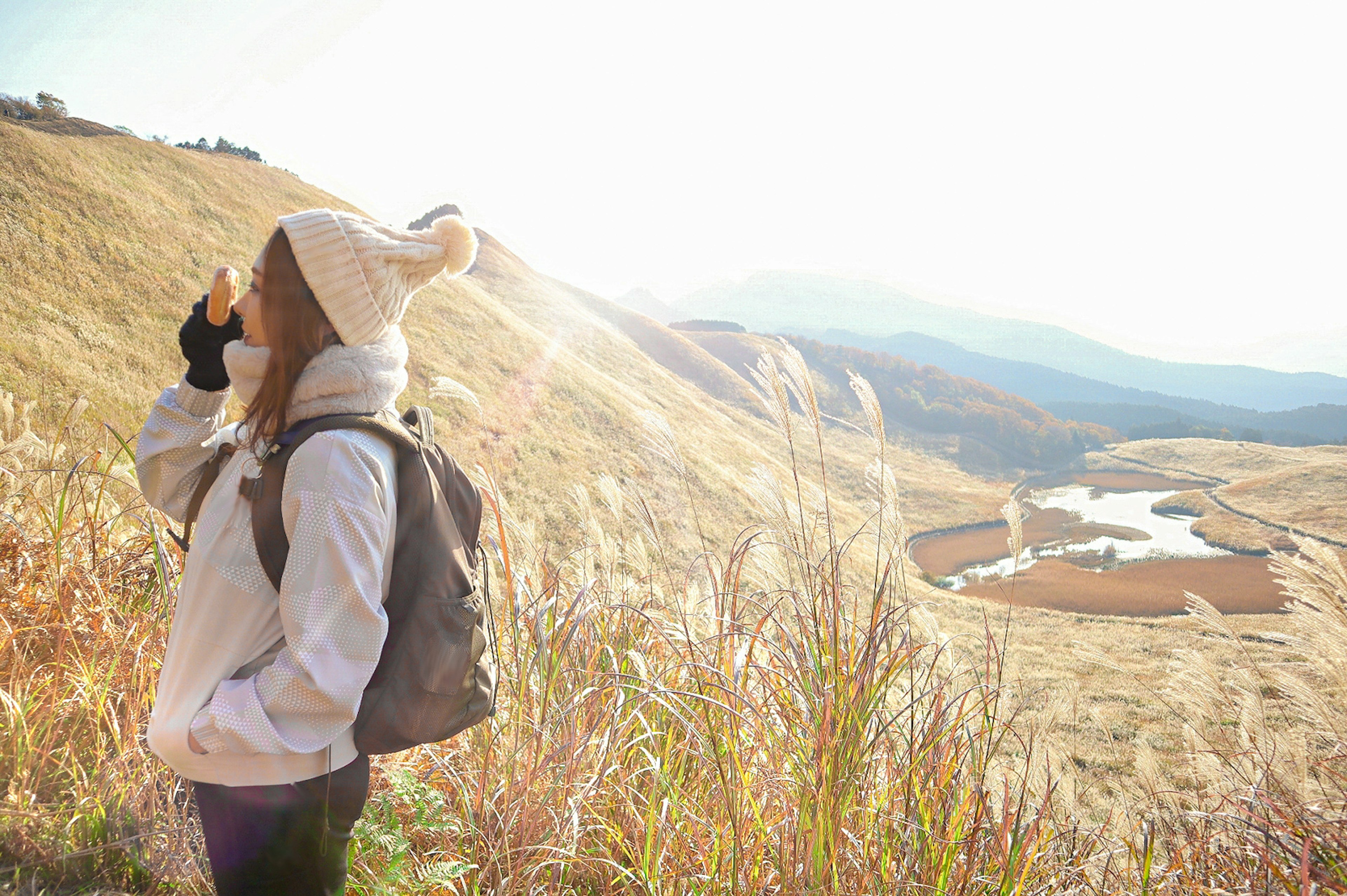 Una mujer con un gorro de invierno y una mochila observa un hermoso paisaje montañoso