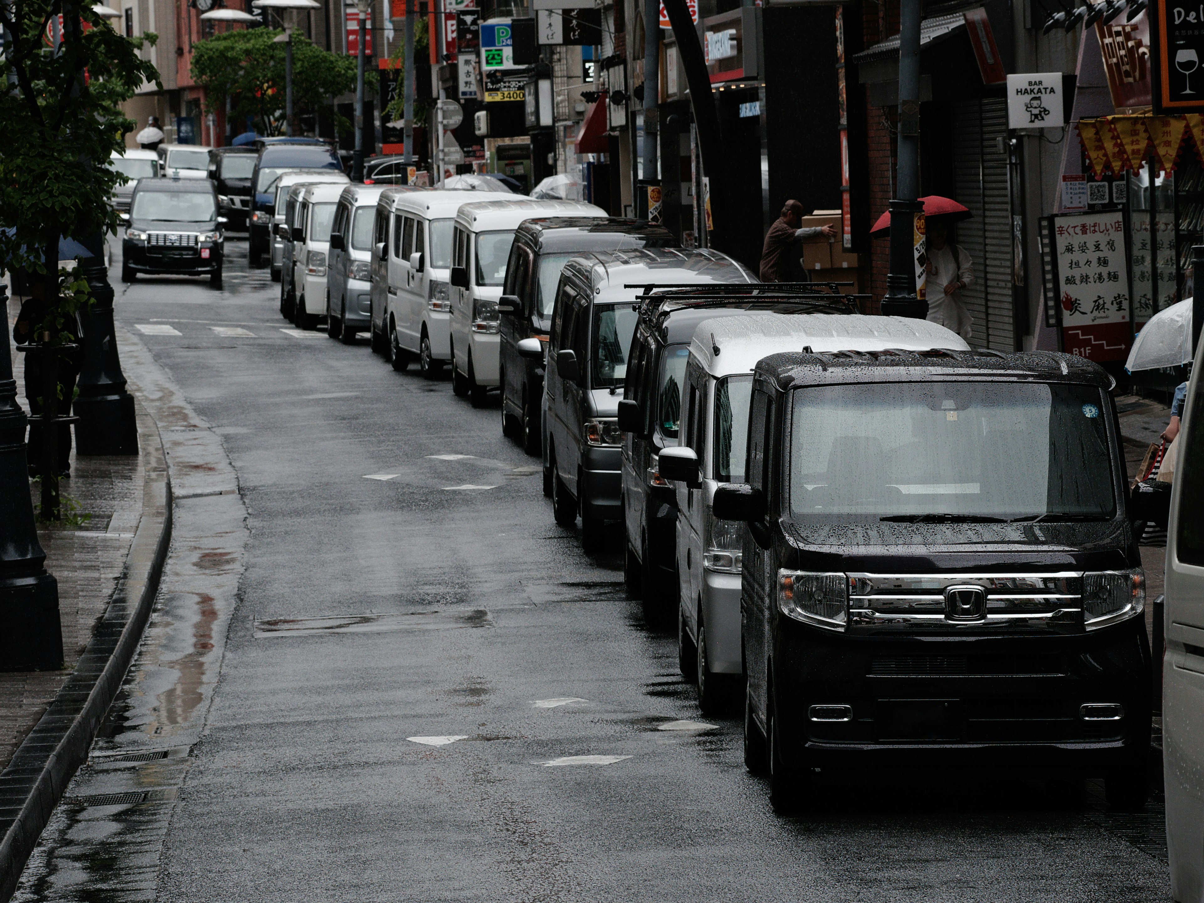 Reihe von weißen und schwarzen Nutzfahrzeugen auf einer nassen Straße