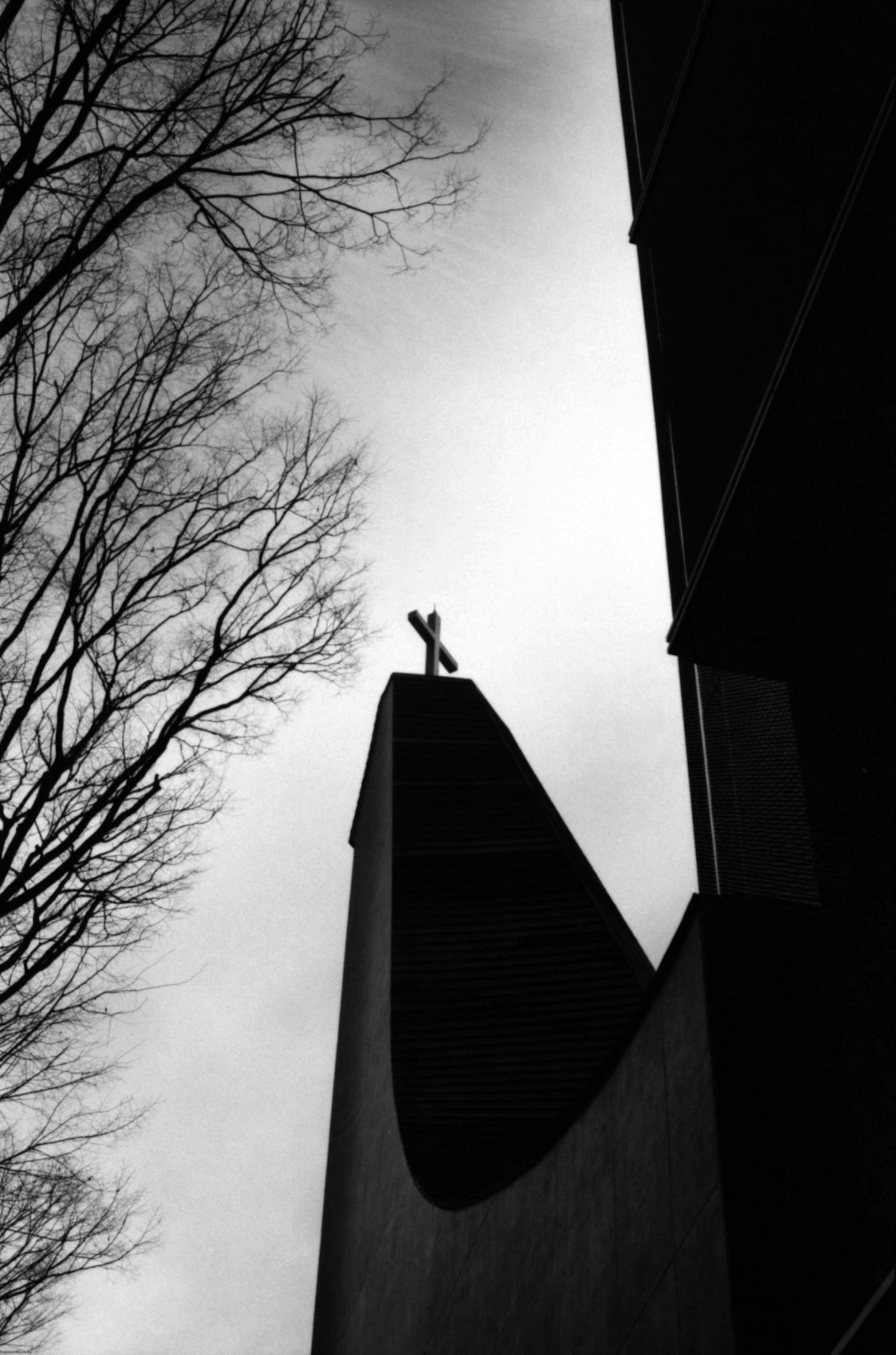 Silhouette of a church steeple with a cross at the top against a cloudy sky