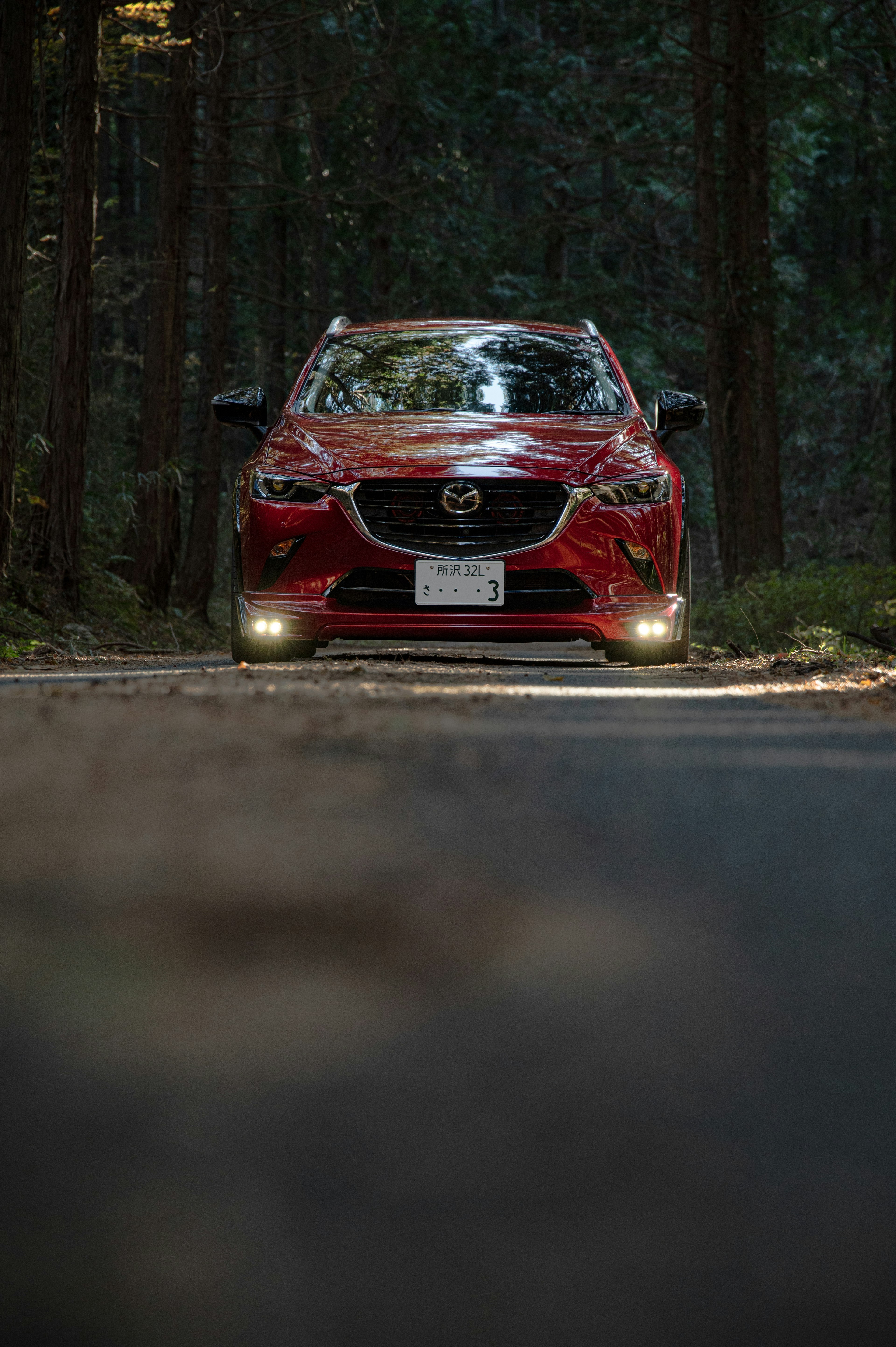 Une voiture rouge garée sur une route dans les bois