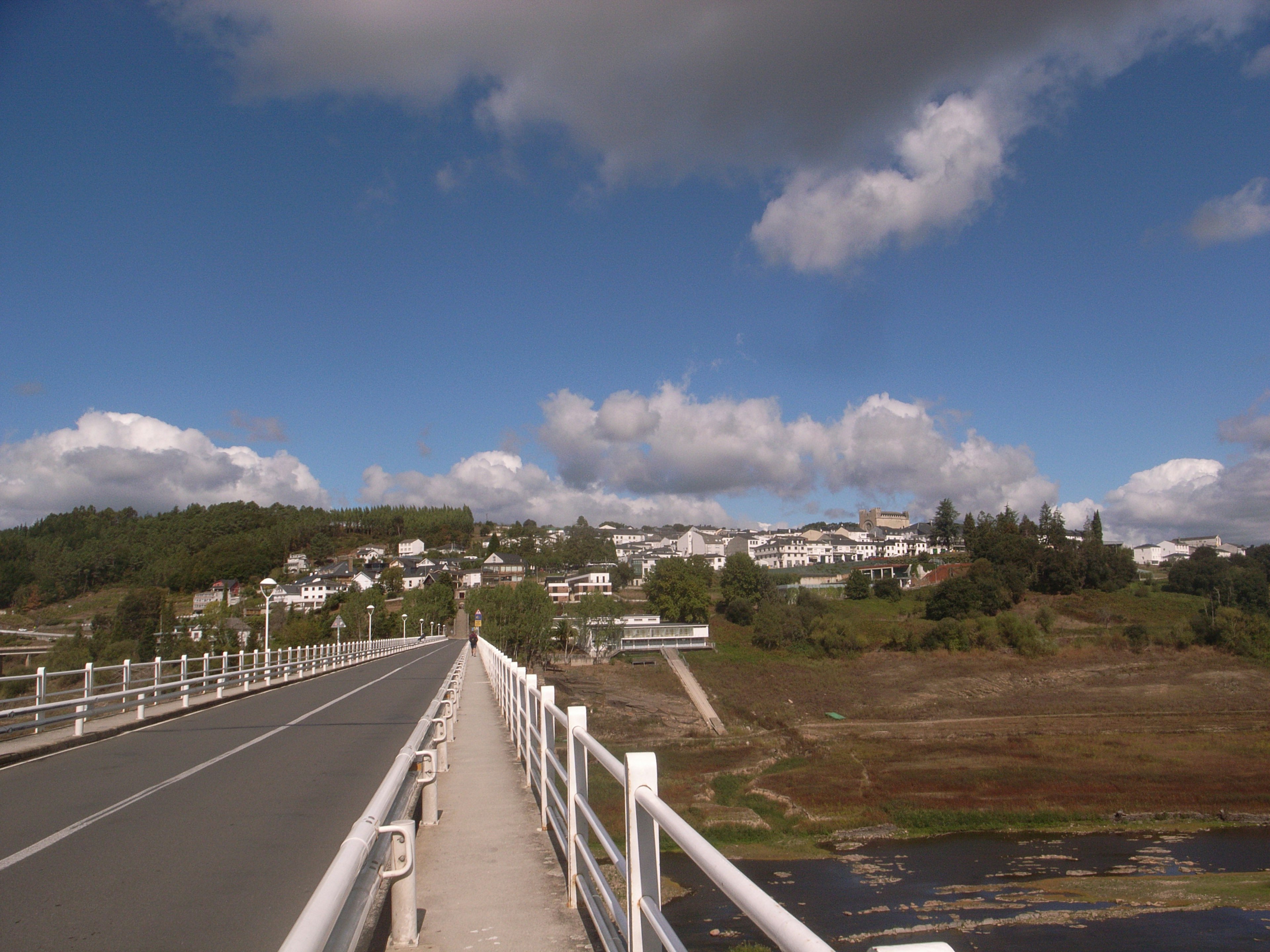 ทิวทัศน์ของสะพานที่มีราวขาวใต้ท้องฟ้าสีฟ้าและเมฆฟูฟ่อง