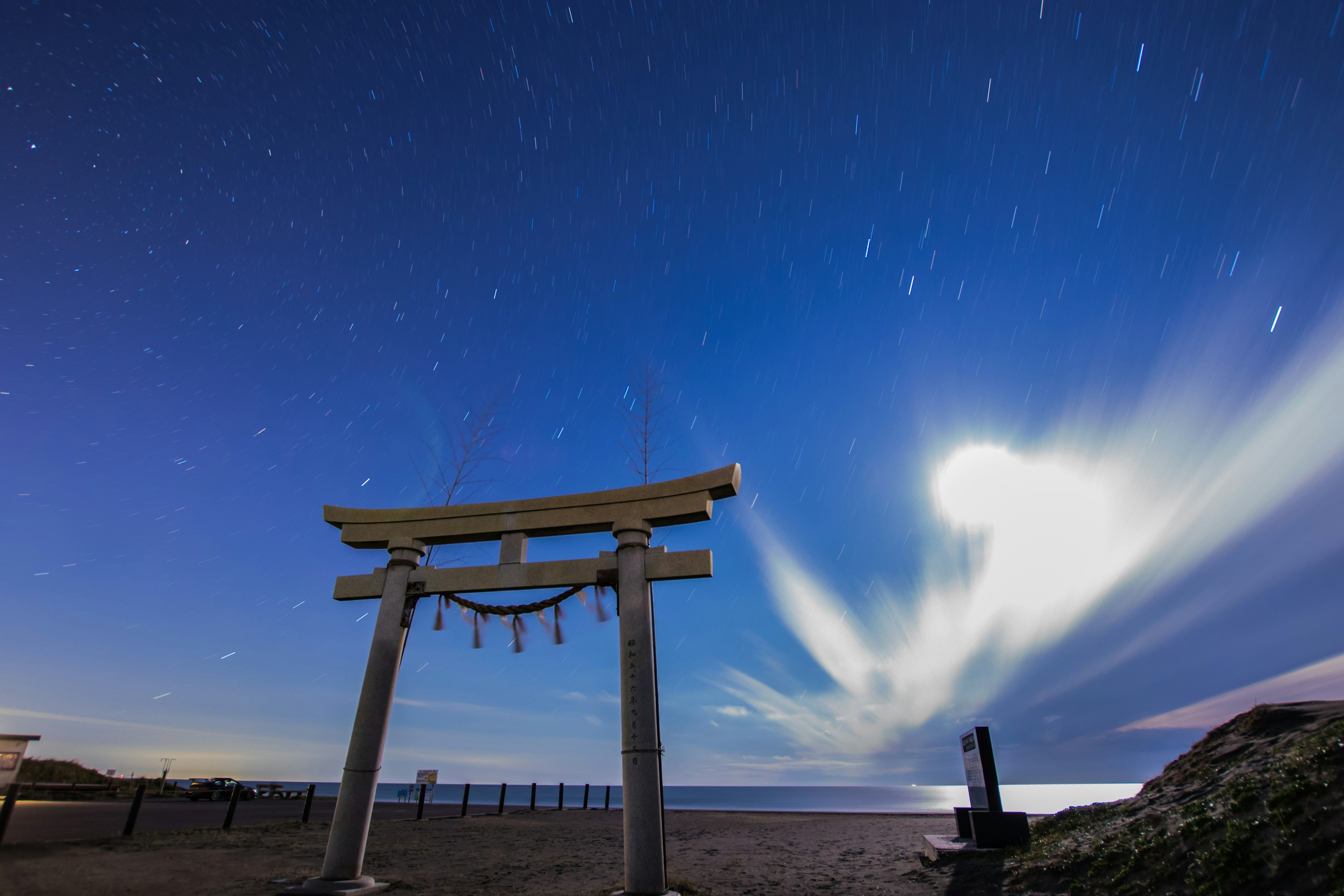 Cổng torii silhouetted trước bầu trời đầy sao với mây và đại dương