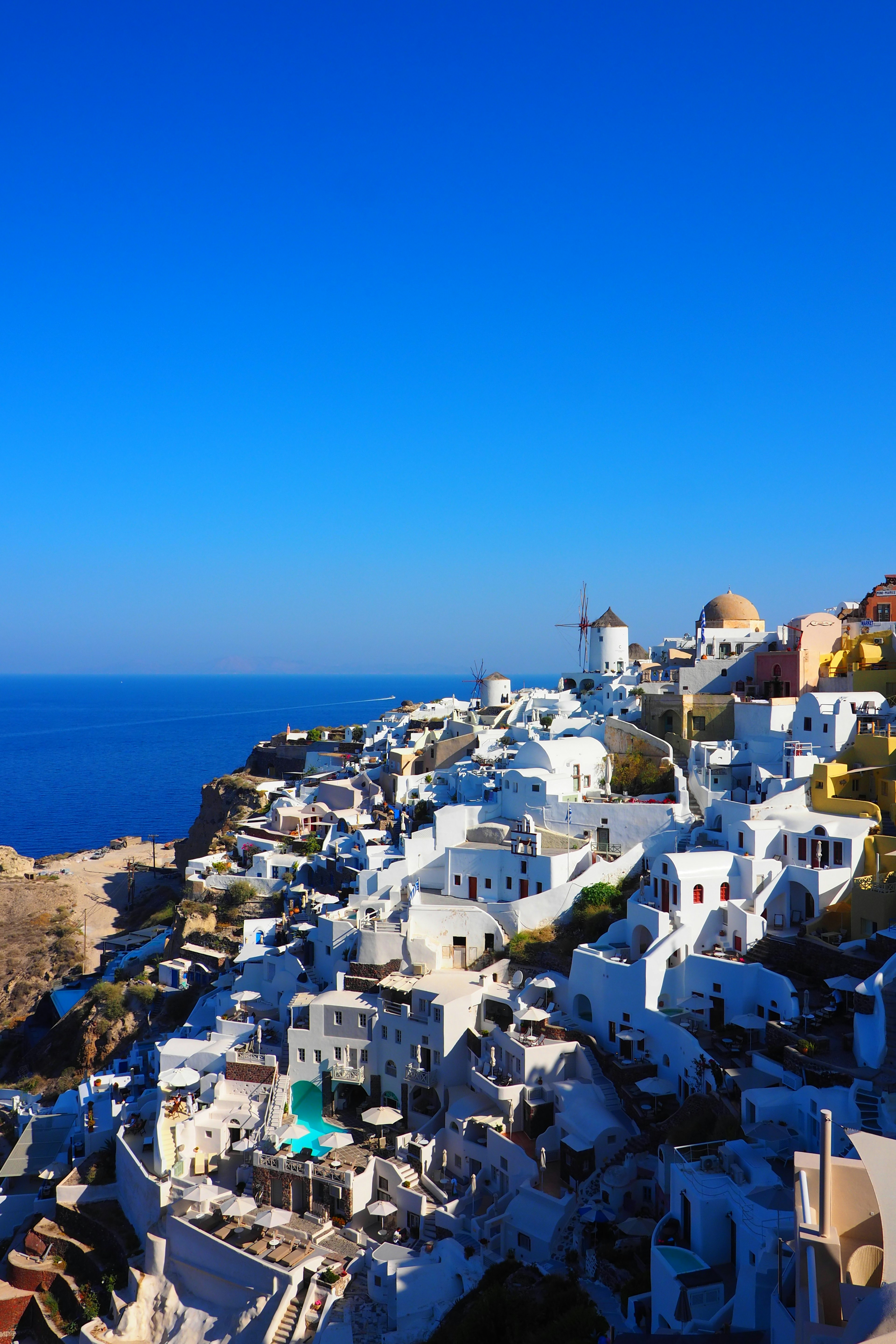 Hermoso paisaje de Santorini con edificios blancos y molinos de viento bajo el cielo azul del Egeo