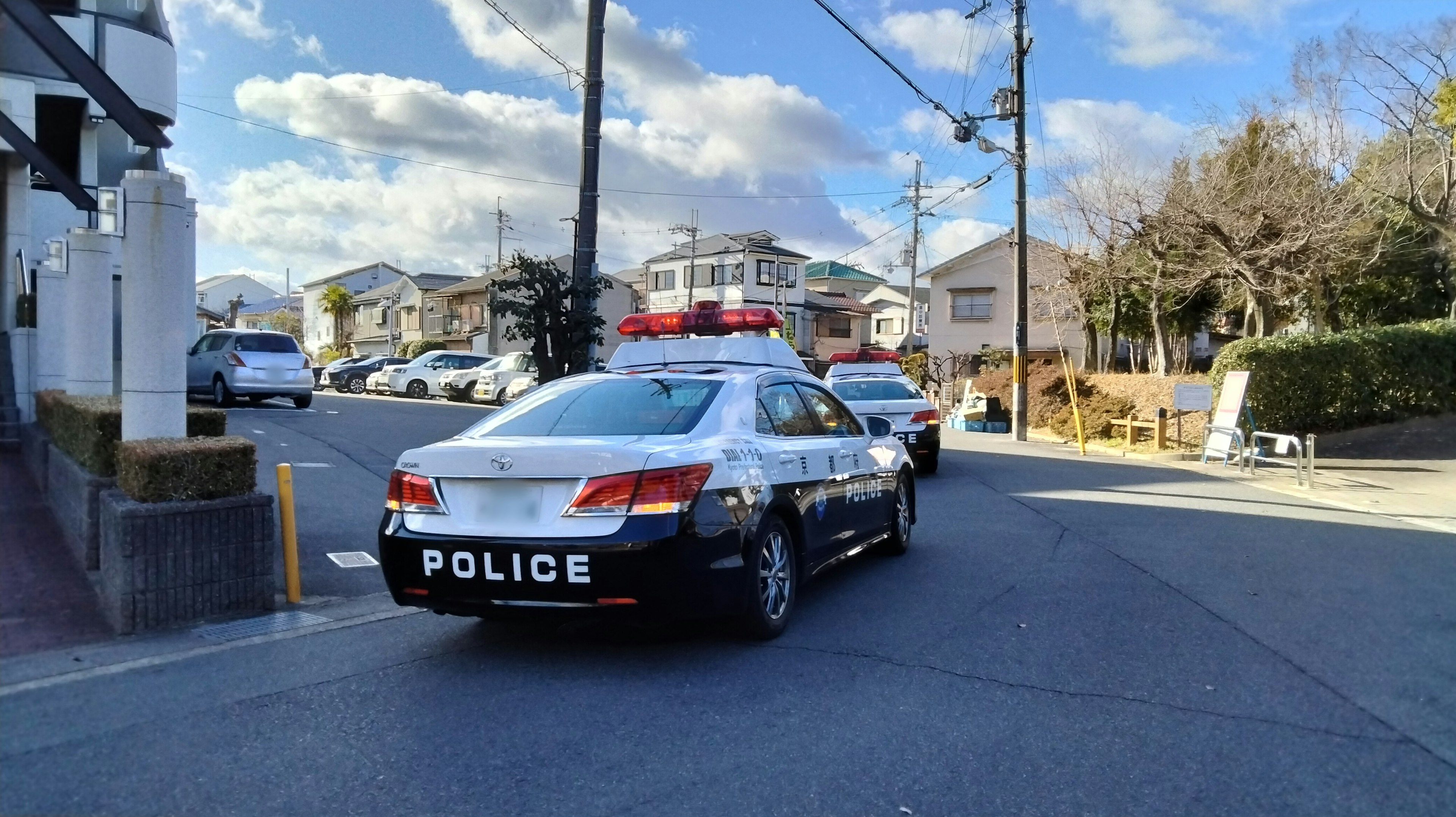 警察車両が通りに停まっている風景と青空