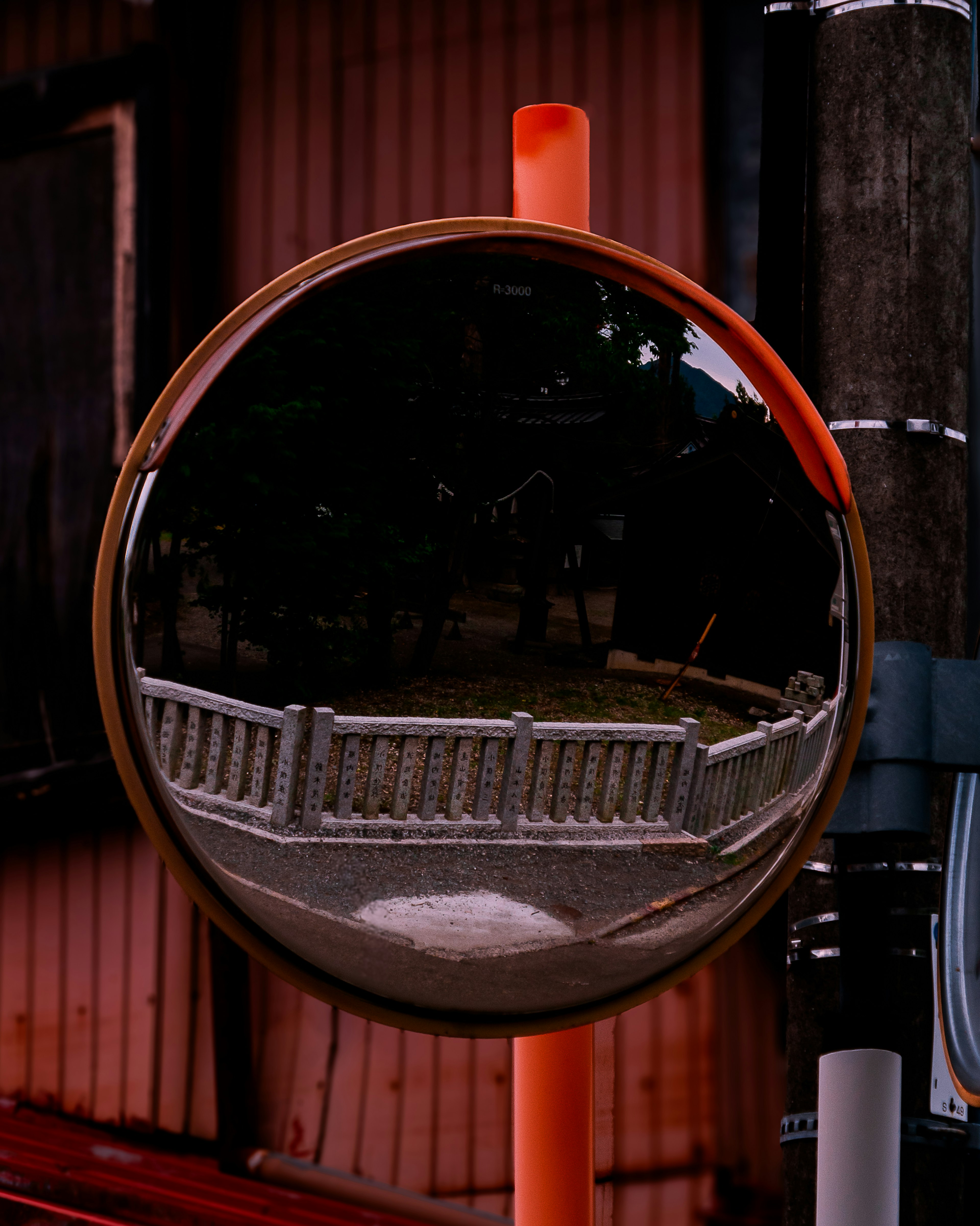 Round mirror with orange border reflecting a scenic view