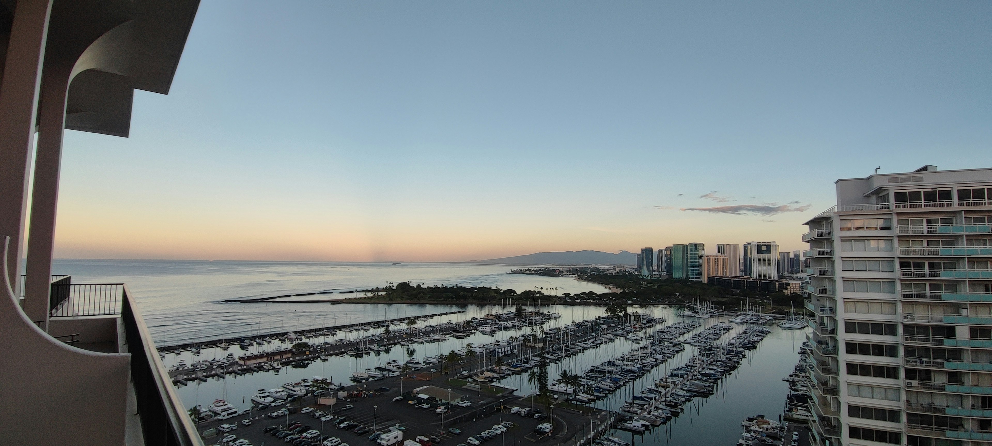 海と都市のパノラマビュー　夕暮れ時の穏やかな空　マリーナと高層ビルが見える