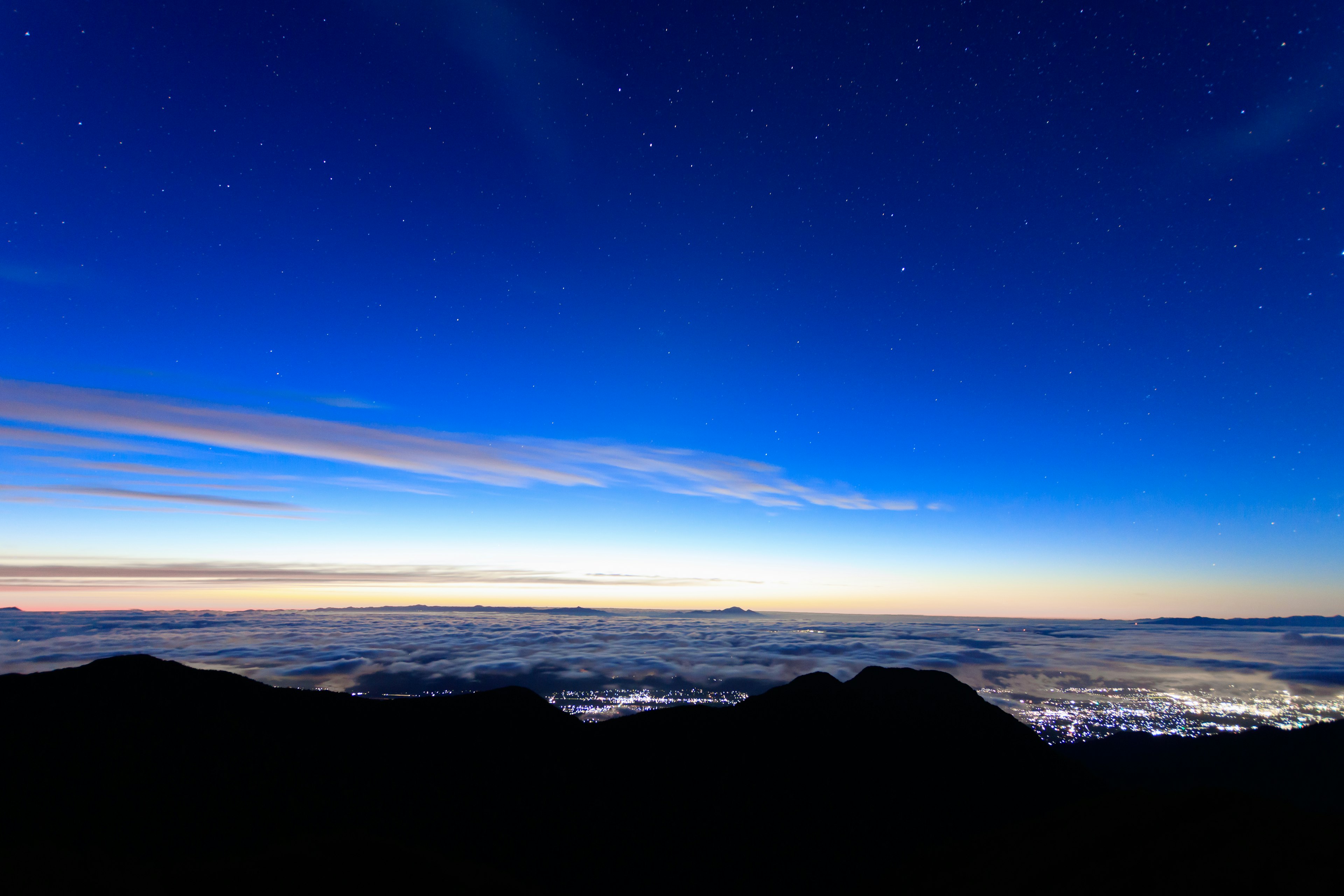 Pemandangan fajar dengan langit biru dan bintang berkelap-kelip gunung dan lautan awan