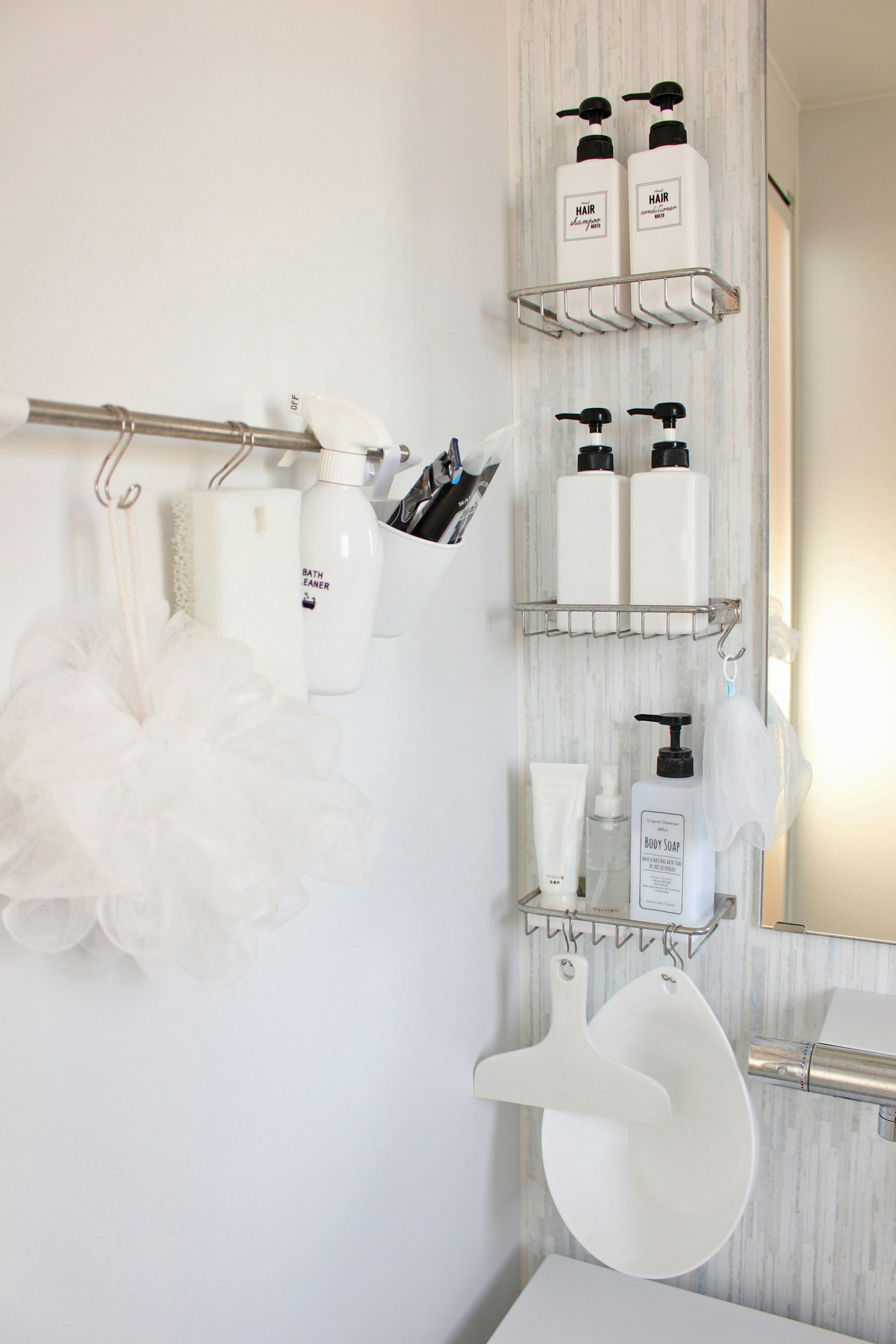 White bathroom wall with neatly arranged shampoo and body wash bottles alongside bath accessories