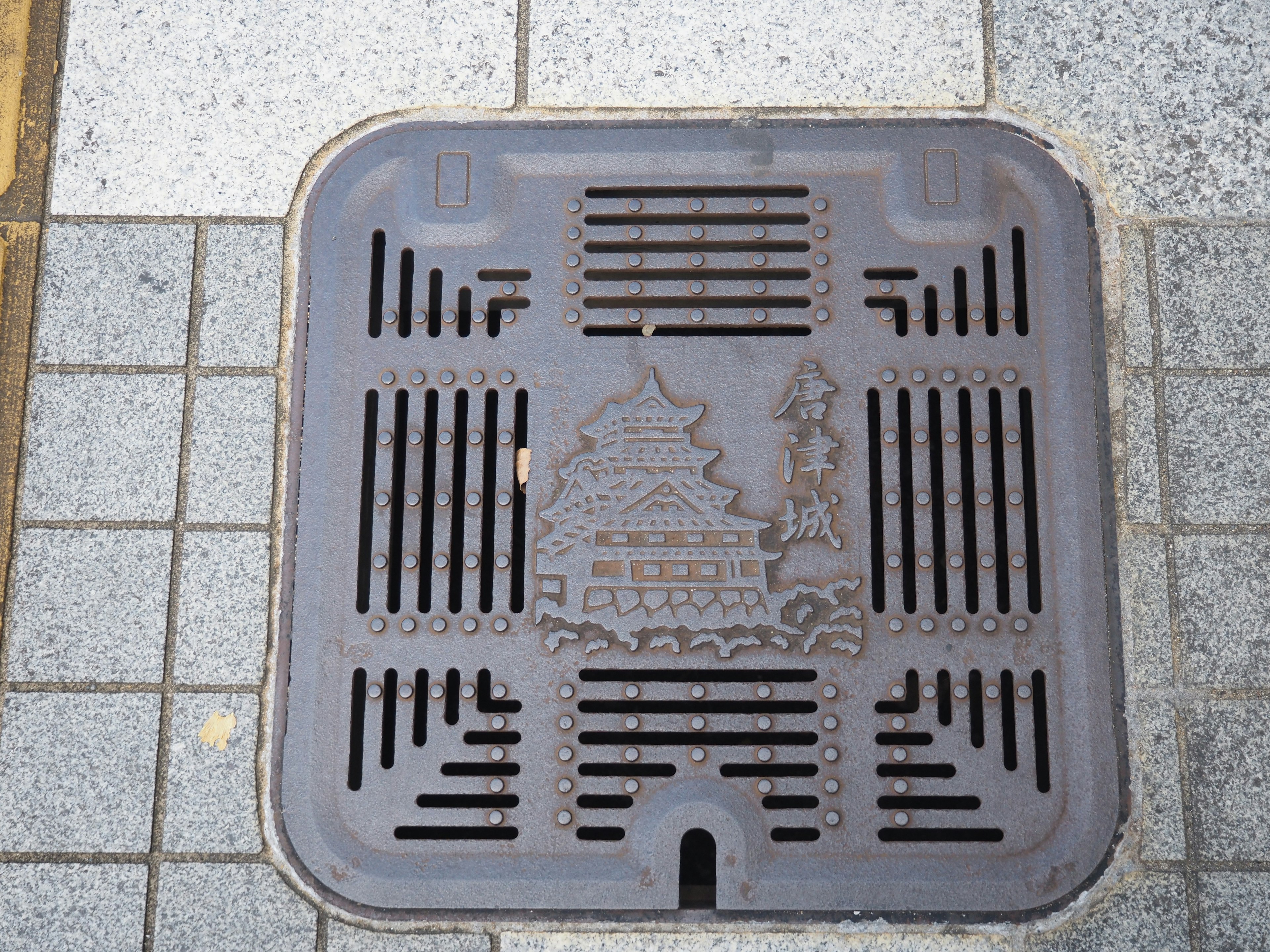 Decorative manhole cover featuring a traditional building on city pavement