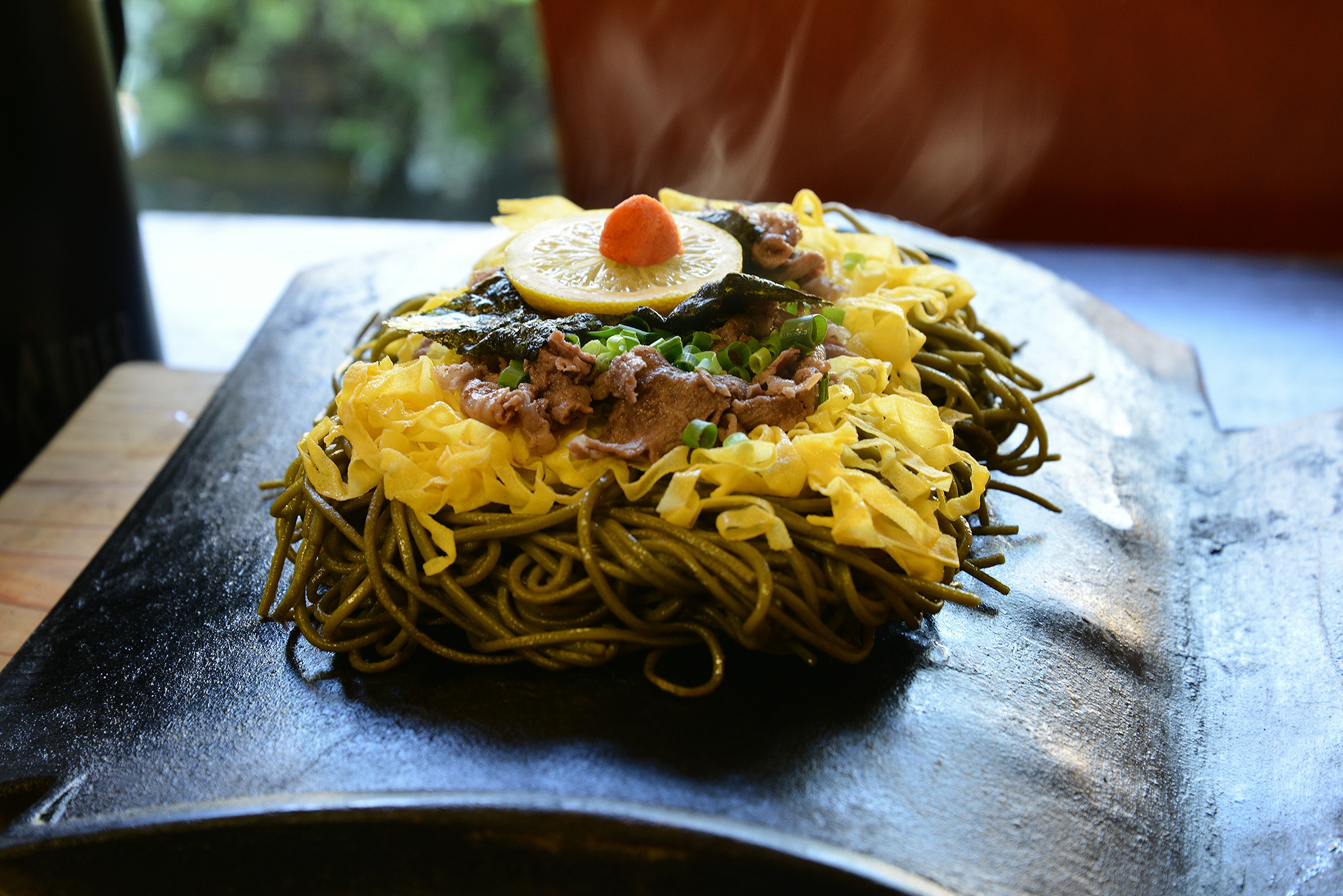 Plato de fideos salteados con huevo y carne encima