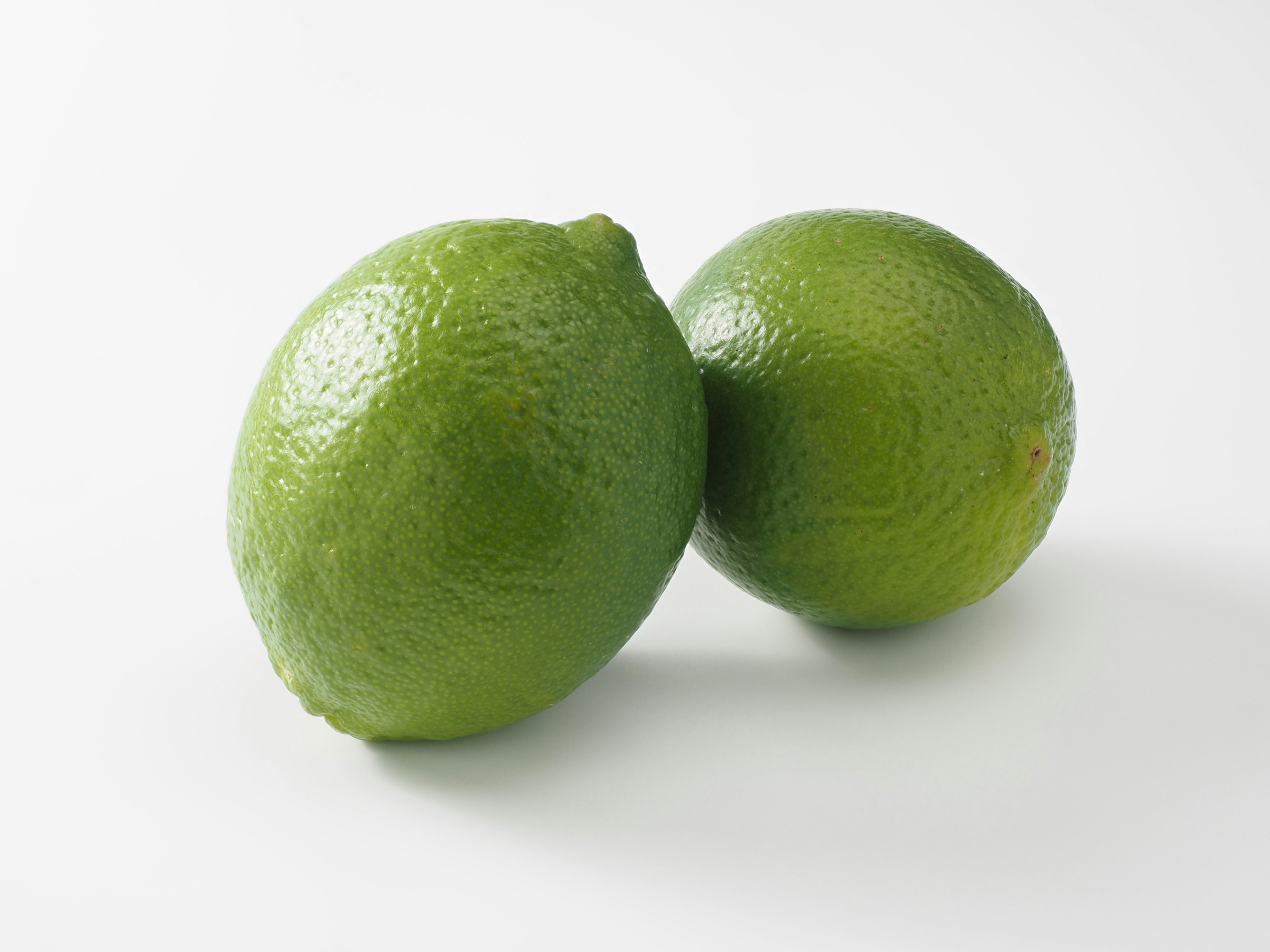 Two fresh limes positioned on a white background