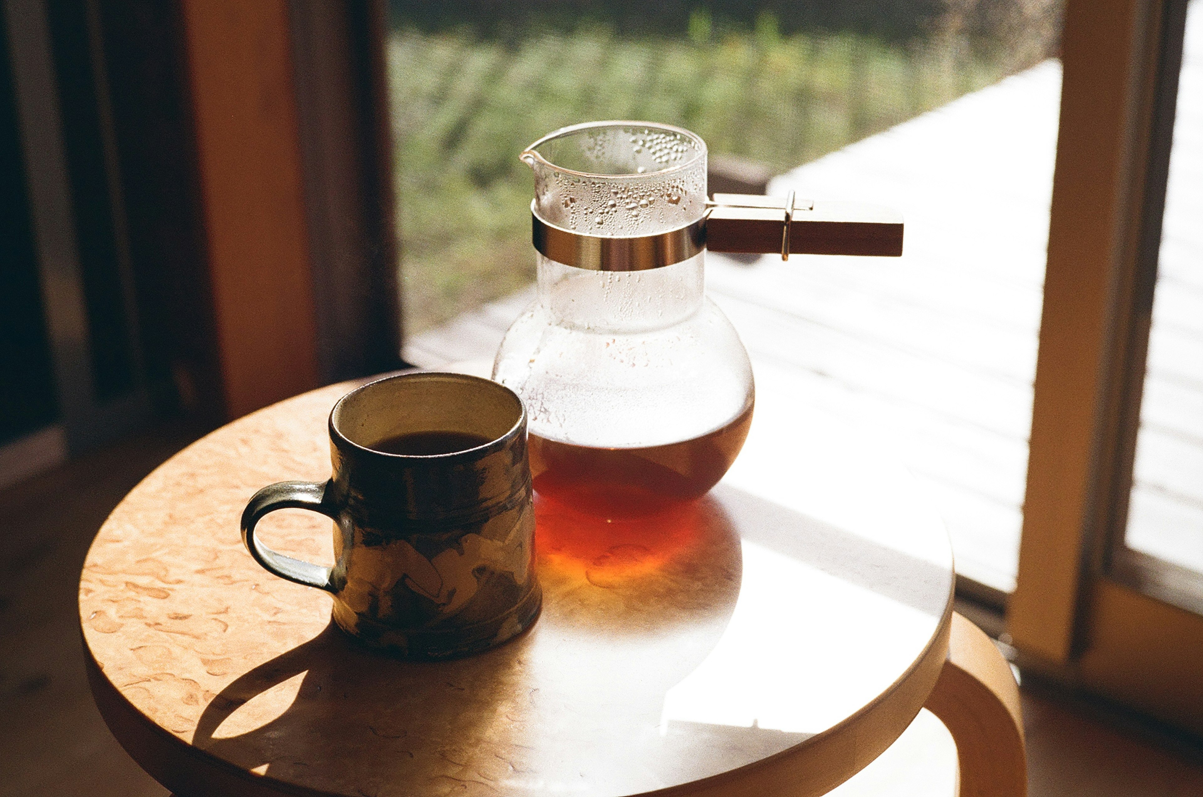 Eine Teekanne und eine Tasse auf einem Holztisch in einem hellen Raum mit Sonnenlicht