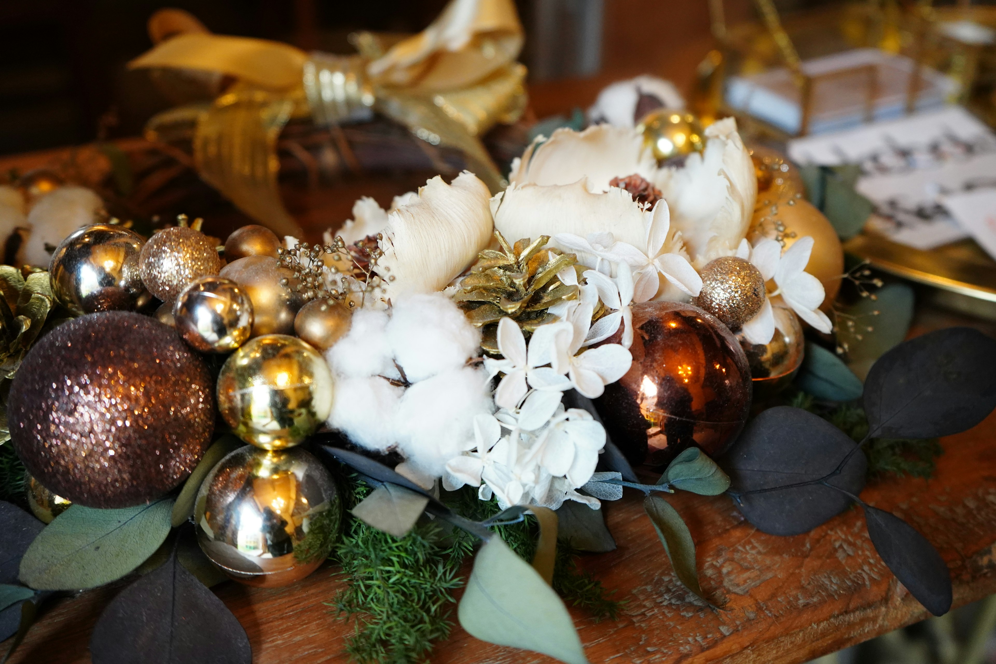 Christmas wreath featuring gold and brown decorative balls and white flowers