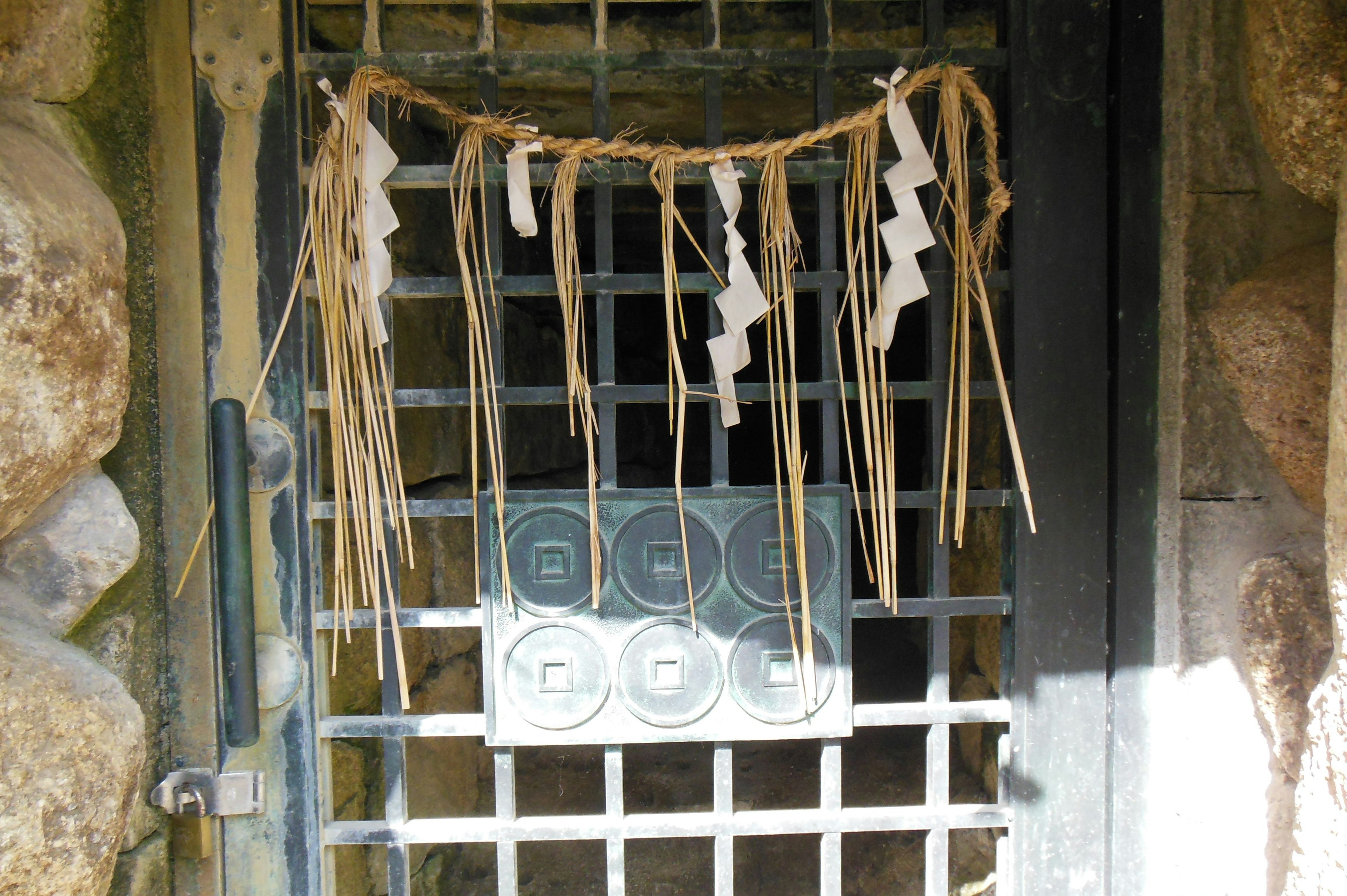 Elementos decorativos de hierba y papel en una puerta de rejilla metálica