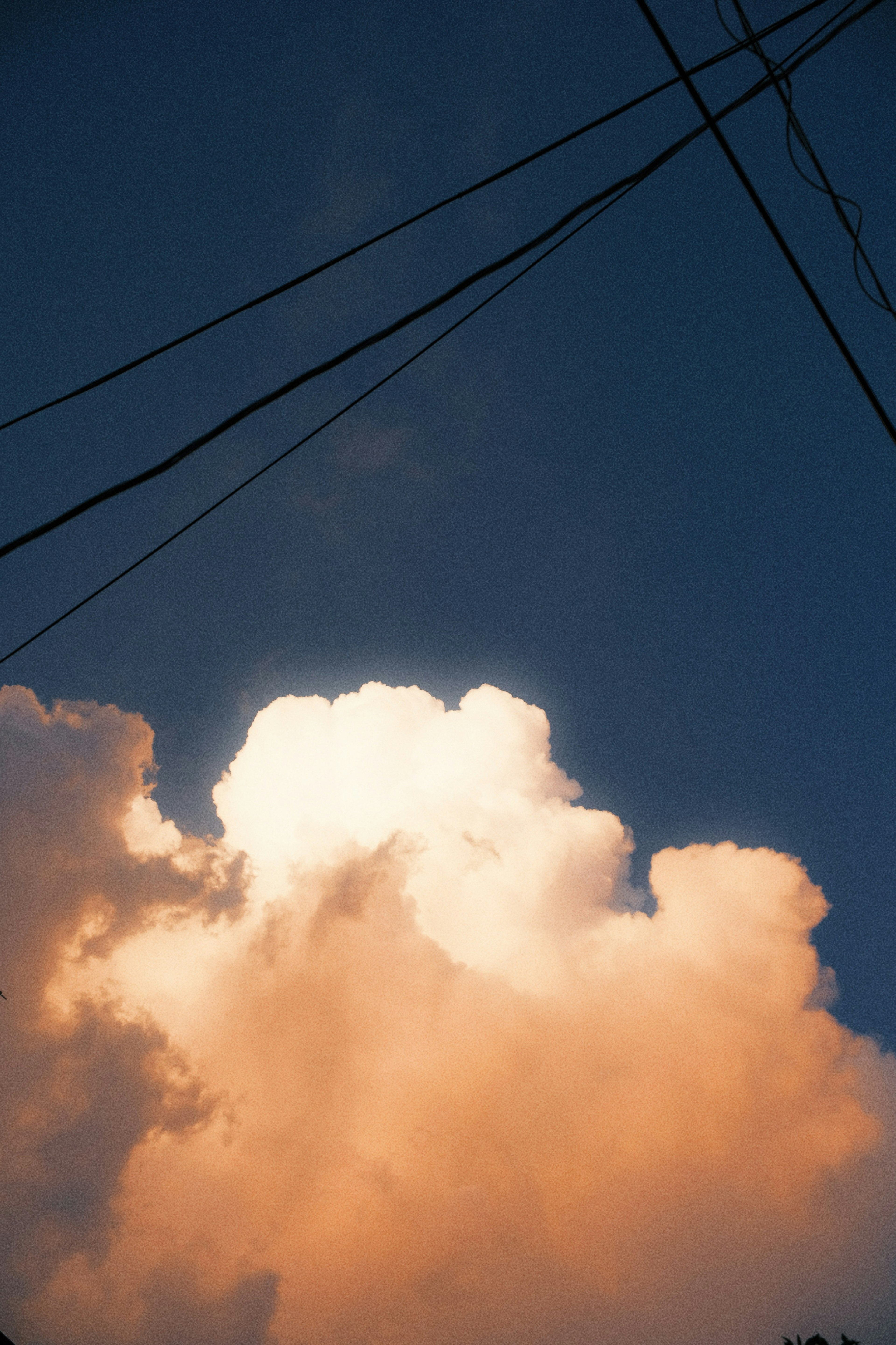 Awan oranye di langit biru dengan kabel listrik